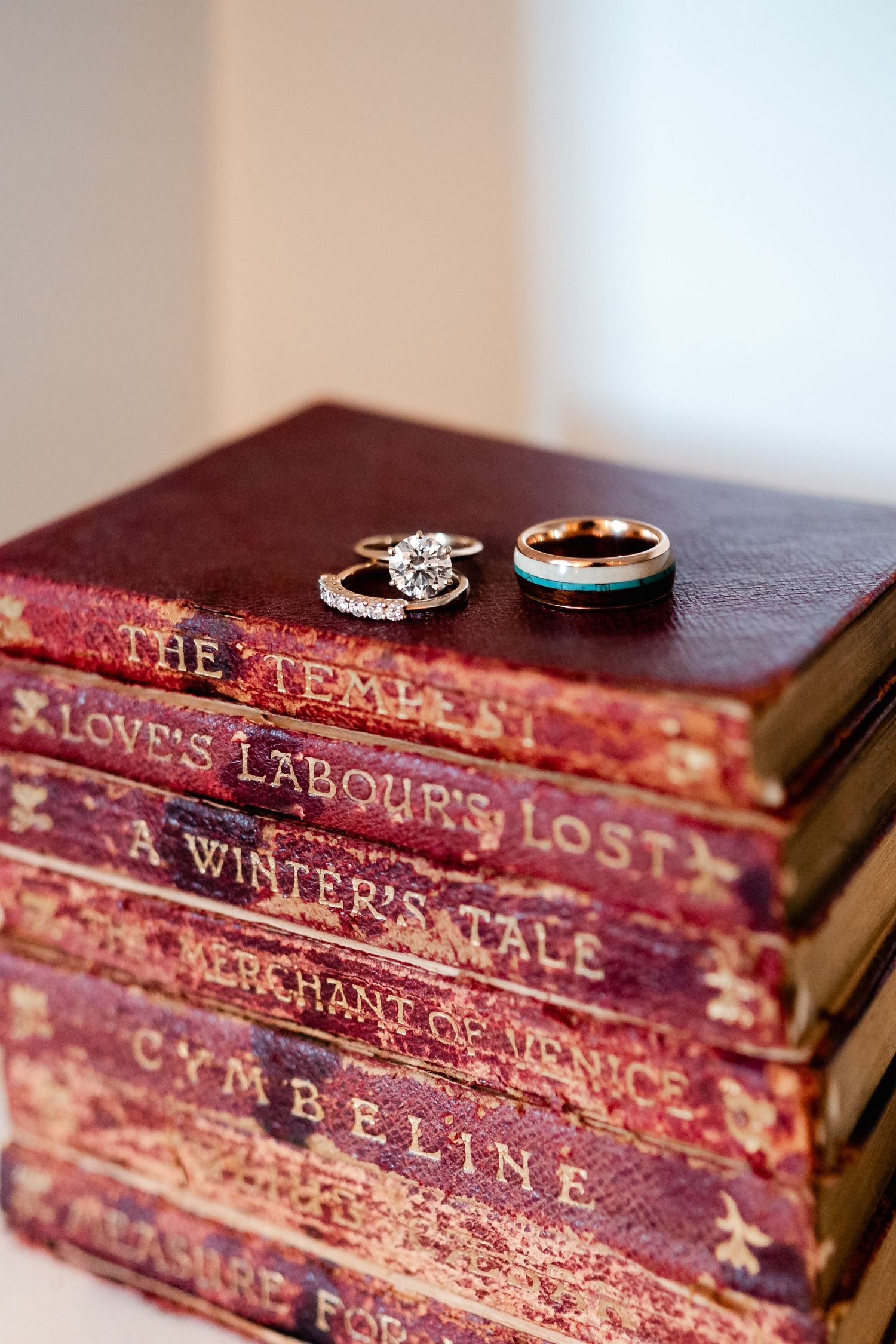 Vintage red leather books with wedding rings displayed on top.
