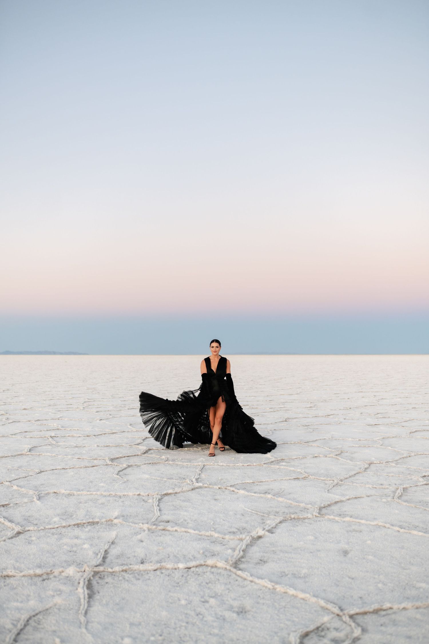 Utah Salt Flats Photographer. Flowing black dress with dramatic movement captured on white salt flats against pastel sky.