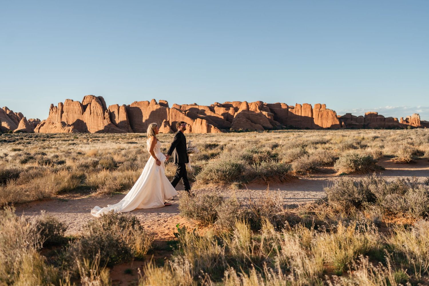 A scenic panoramic view of red rock formations at Arches National Park in Utah during golden hour.