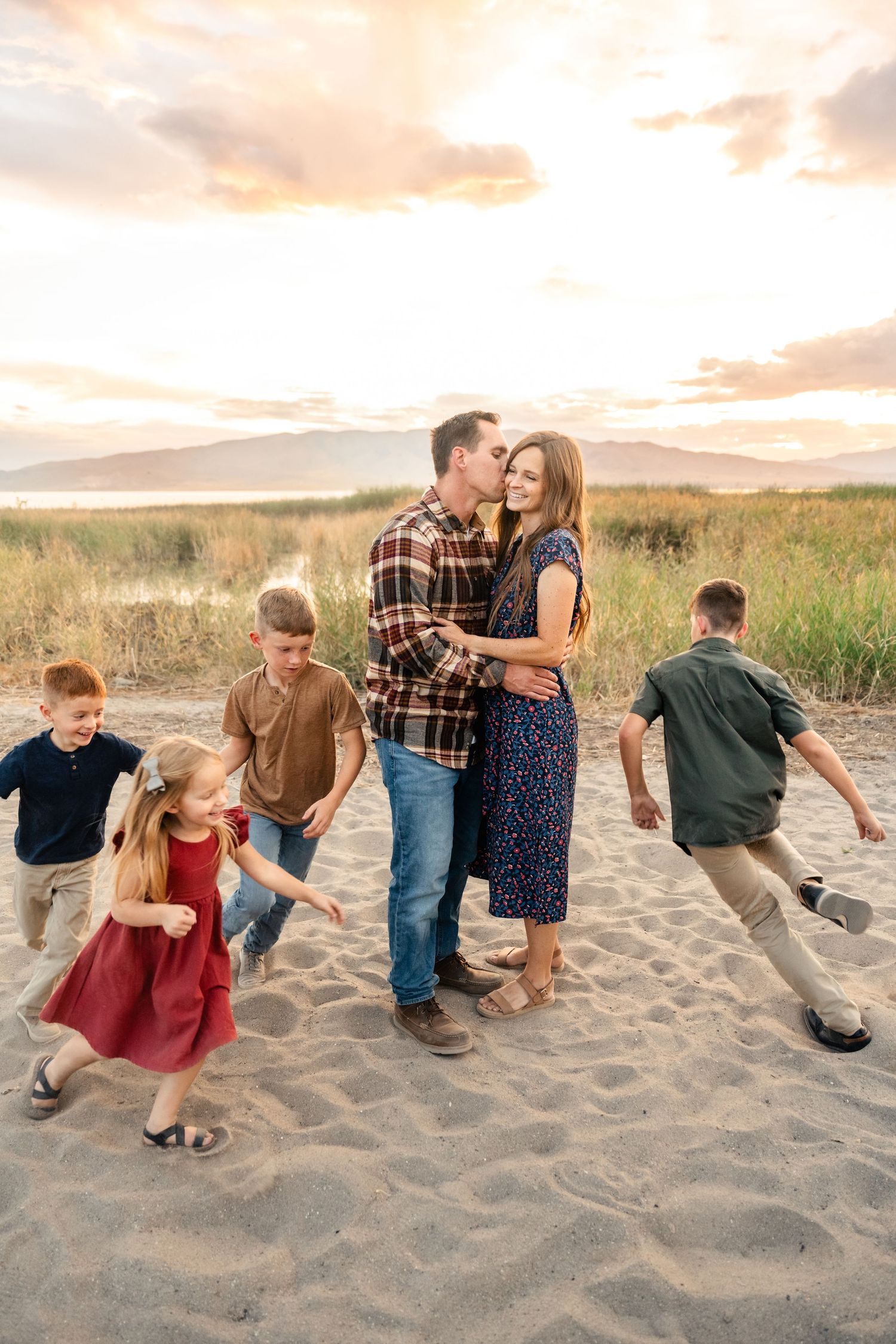 A series of candid beach photos showing a couple and children playing in the sand at sunset.