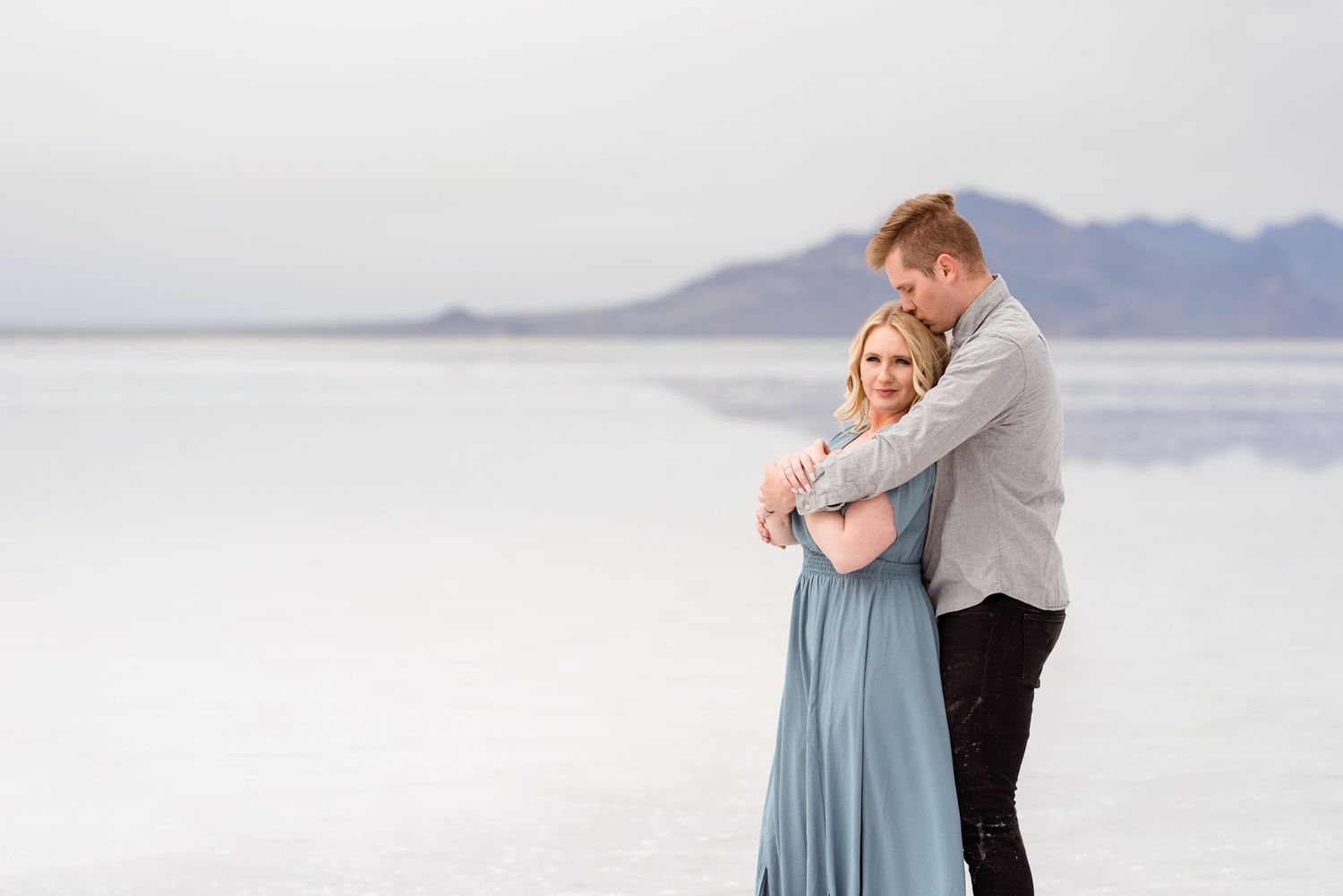 A tender embrace at sunset on the salt flats with mountains in the distance.