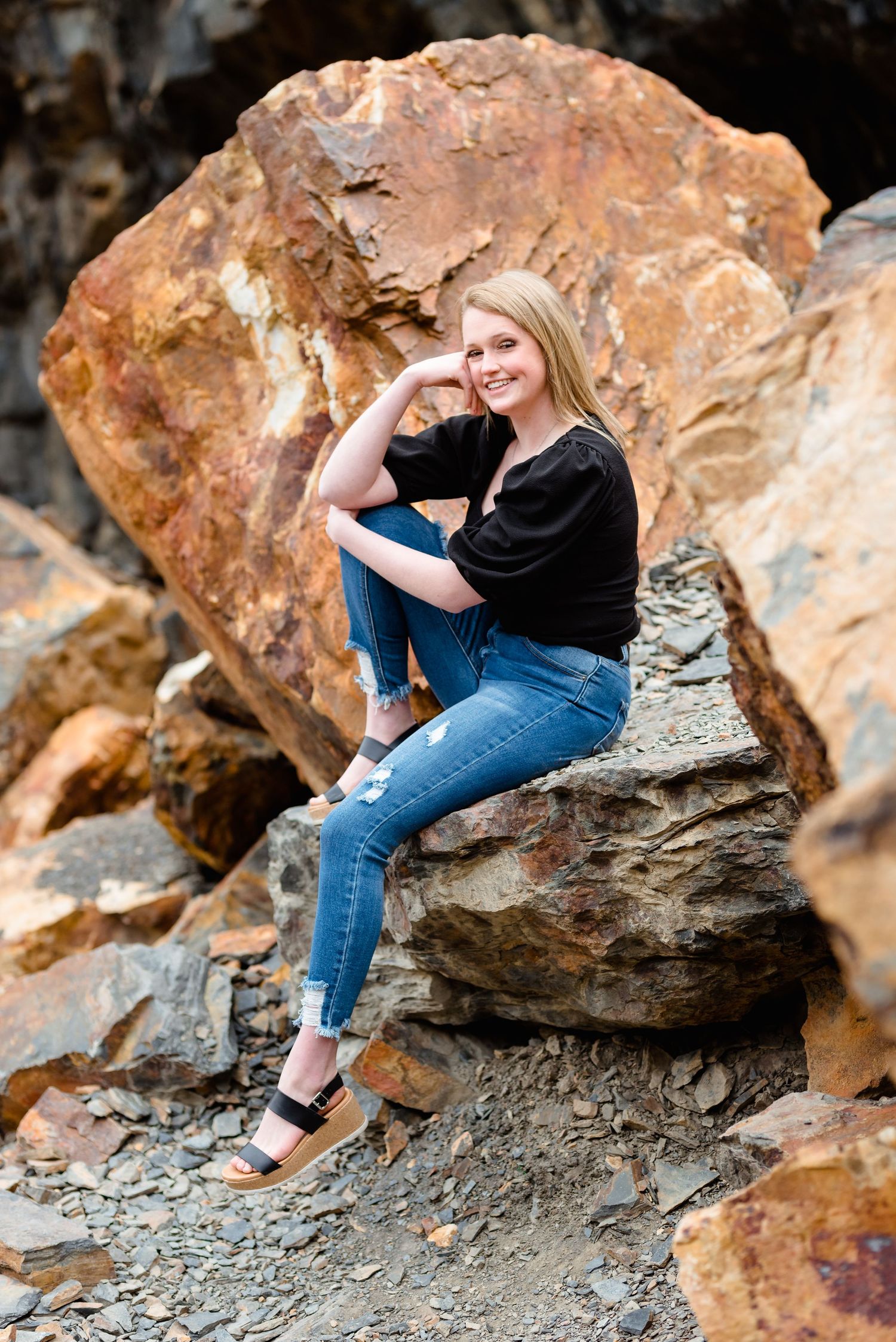 A couple sits together on rugged rock formations during a romantic outdoor photo session.