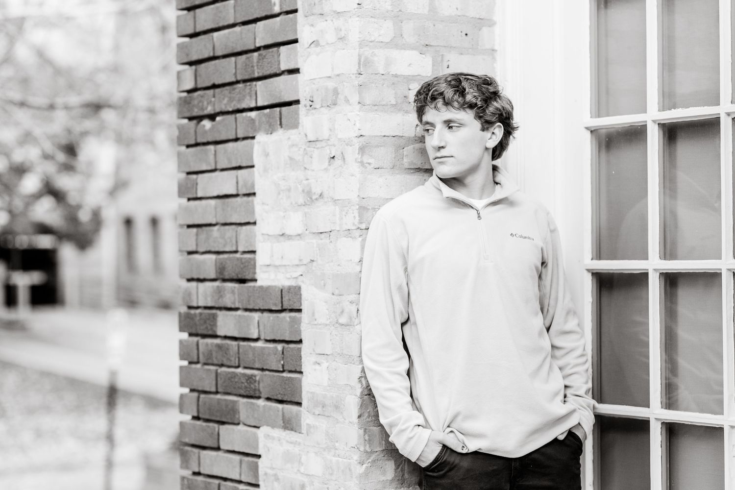 A black and white collage of vintage photographs showing someone posing against brick walls and windows.