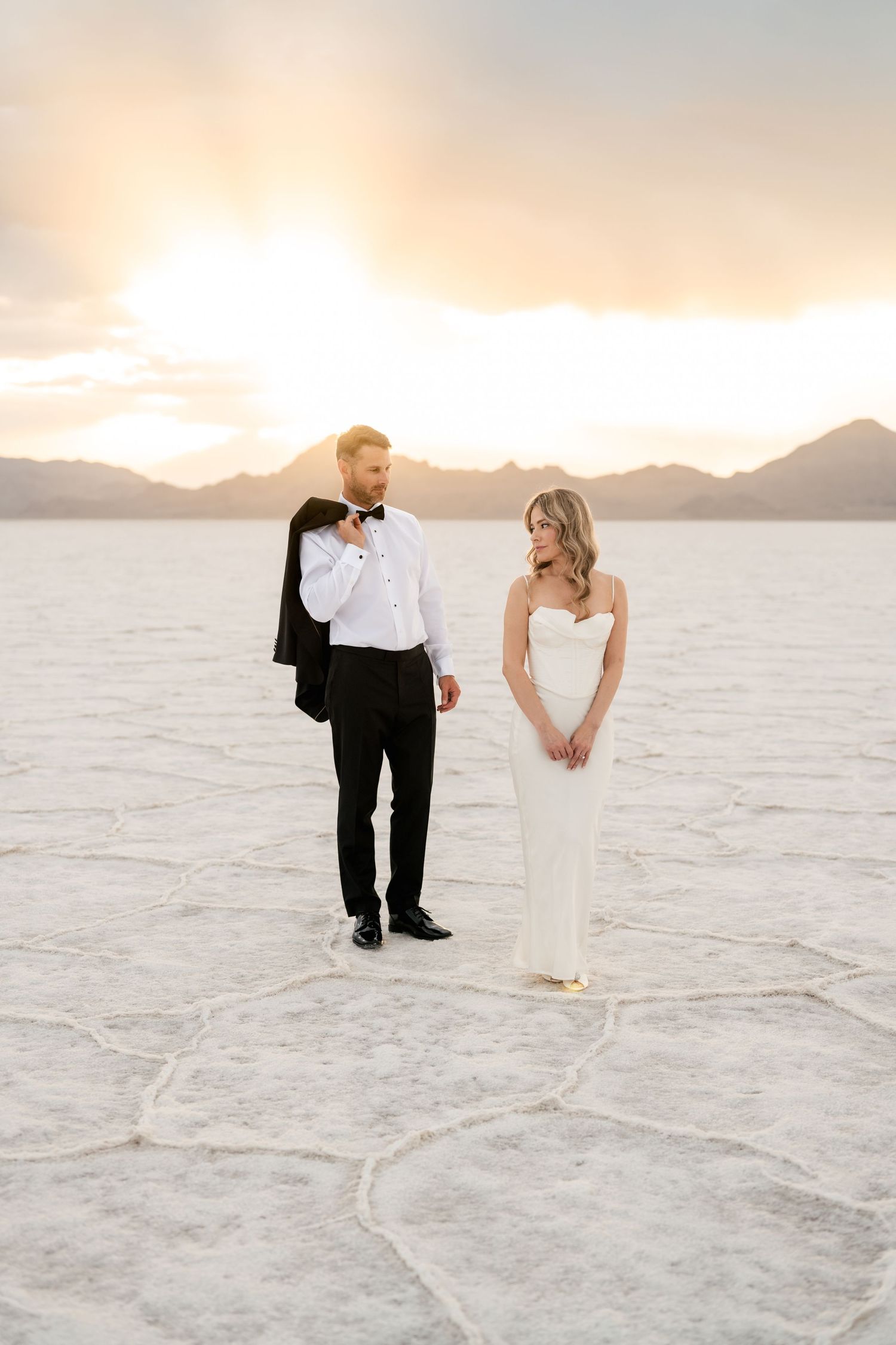 A romantic wedding photoshoot on a white salt flat landscape with mountains in the background at sunset. Salt Flats Elopement Photographer.