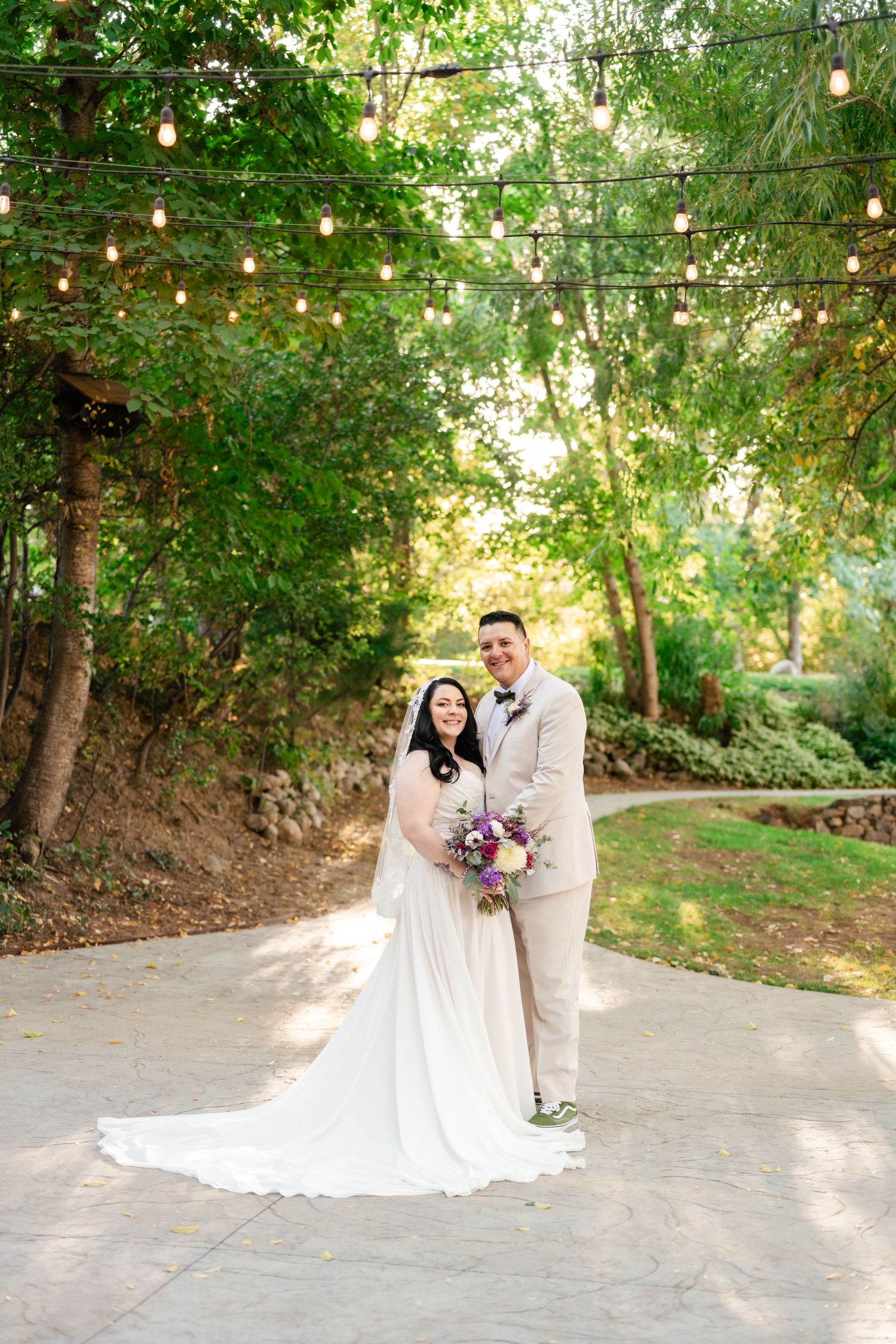 Romantic outdoor wedding scene with string lights overhead and lush greenery creating a magical garden atmosphere.