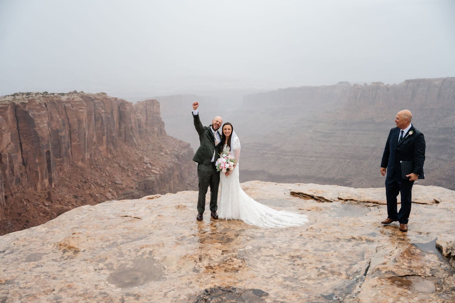 A couple shares an intimate moment at the edge of a vast desert canyon overlook.