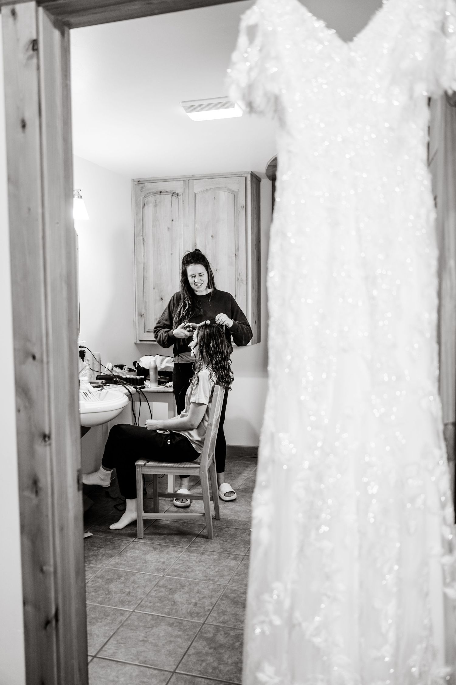 Wedding dresses hanging in a bridal preparation room with white decor.