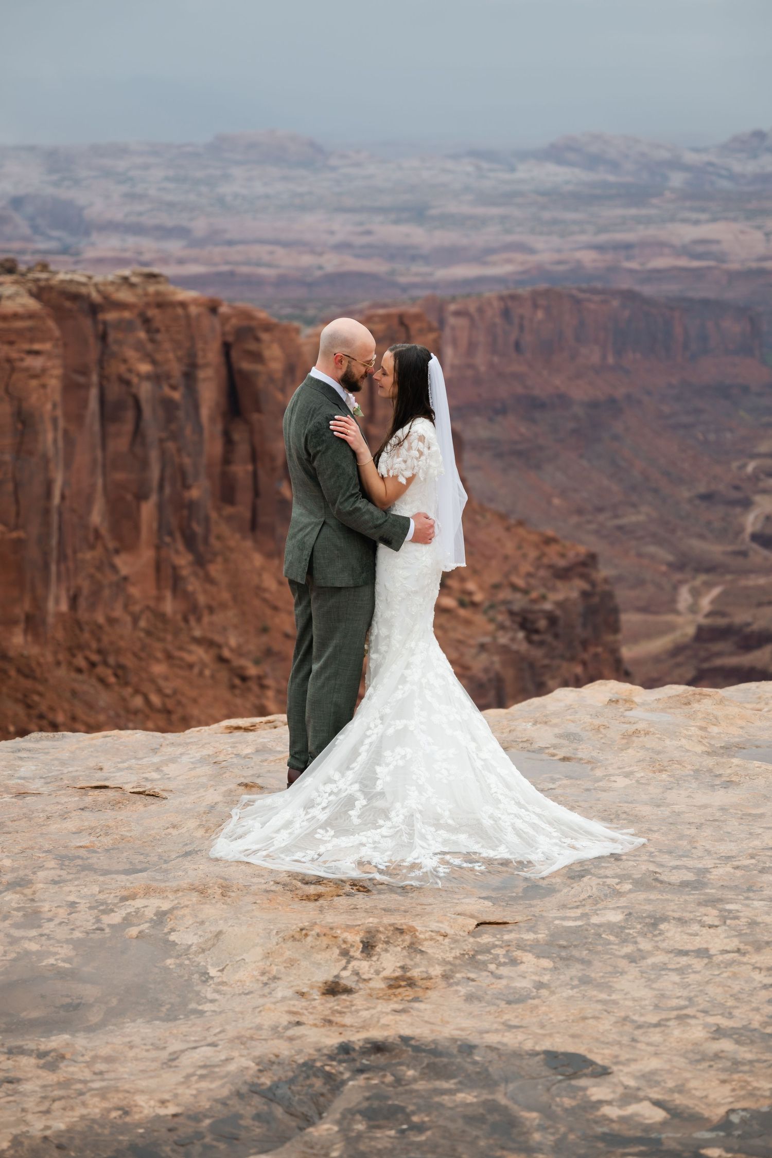 A wedding couple poses against the stunning backdrop of red rock canyons and desert landscape.