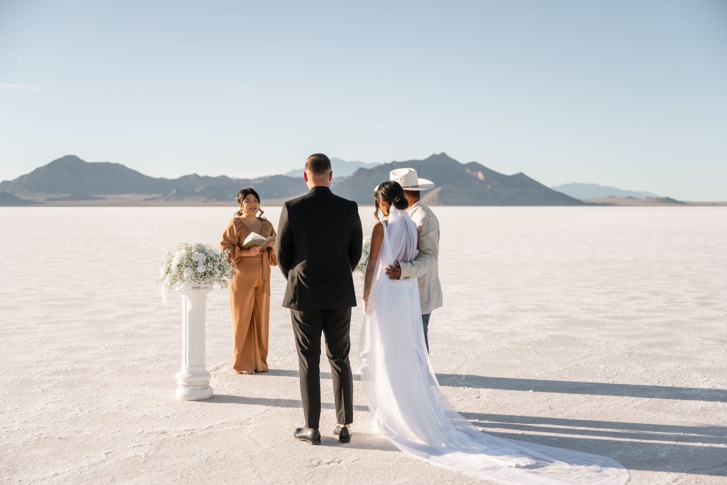 Wedding party silhouettes against the bright white salt flats landscape.