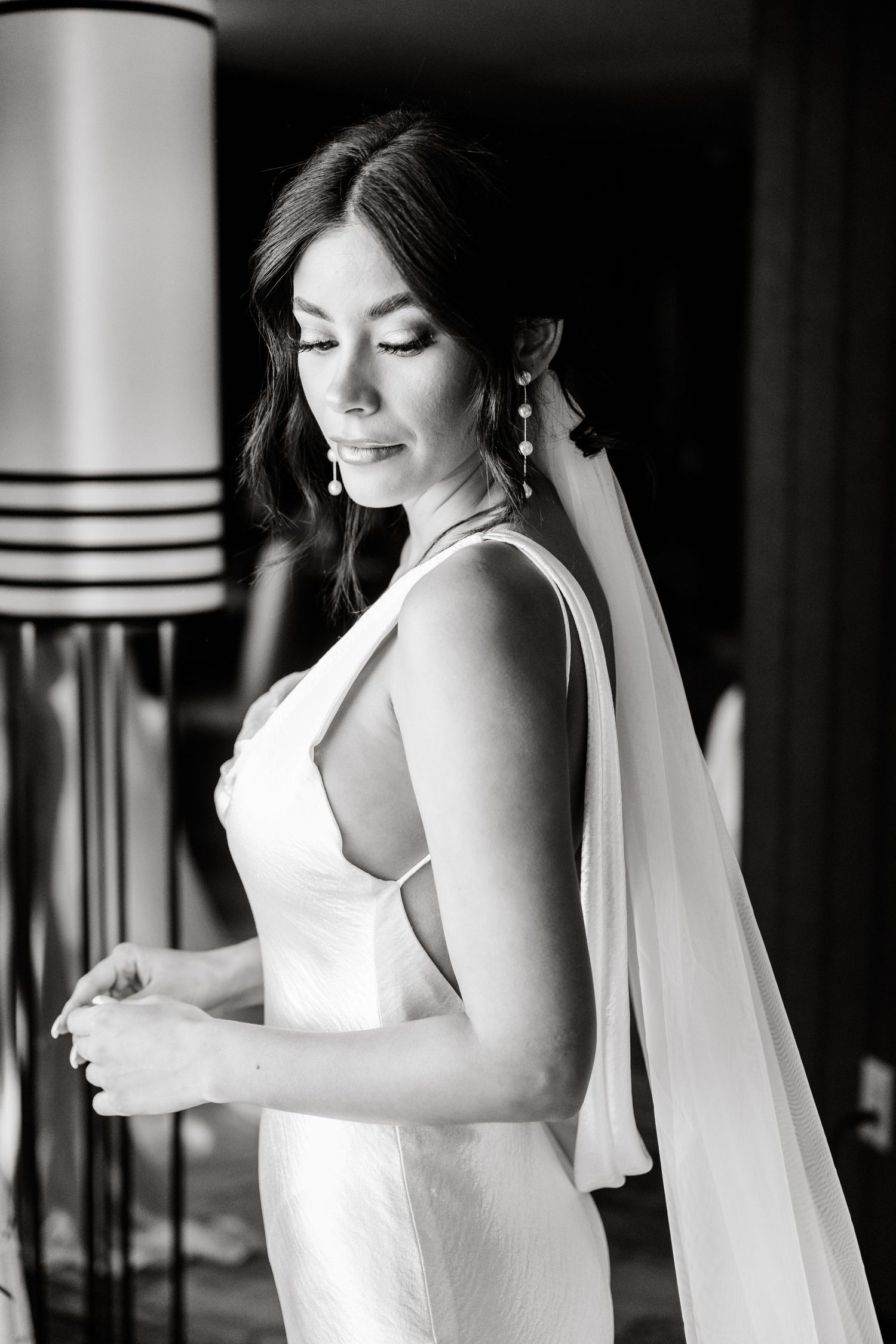 Black and white photos of bride in white dress with flowing veil against dramatic lighting.