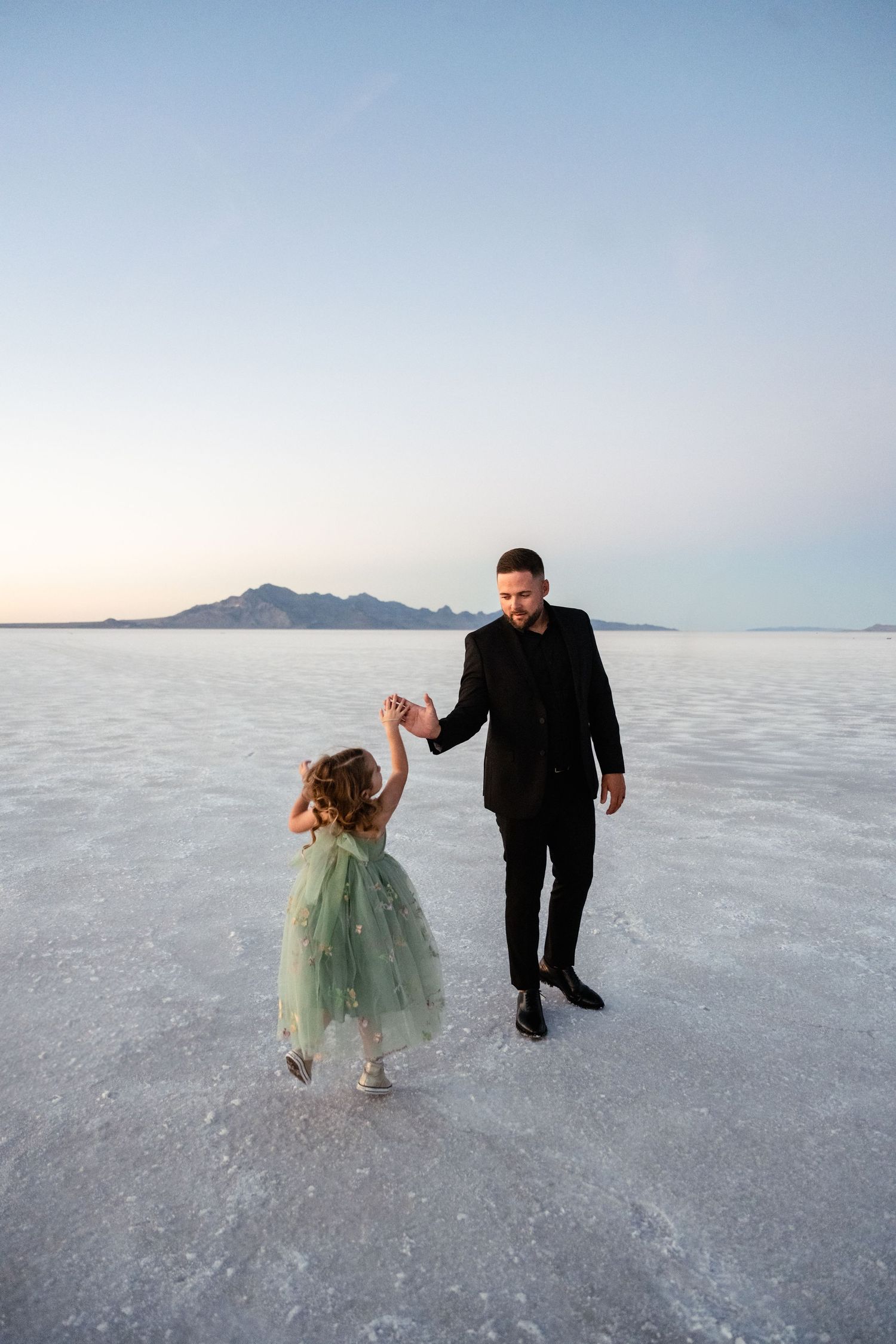 Two figures dance playfully on the stark white surface of the Bonneville Salt Flats.