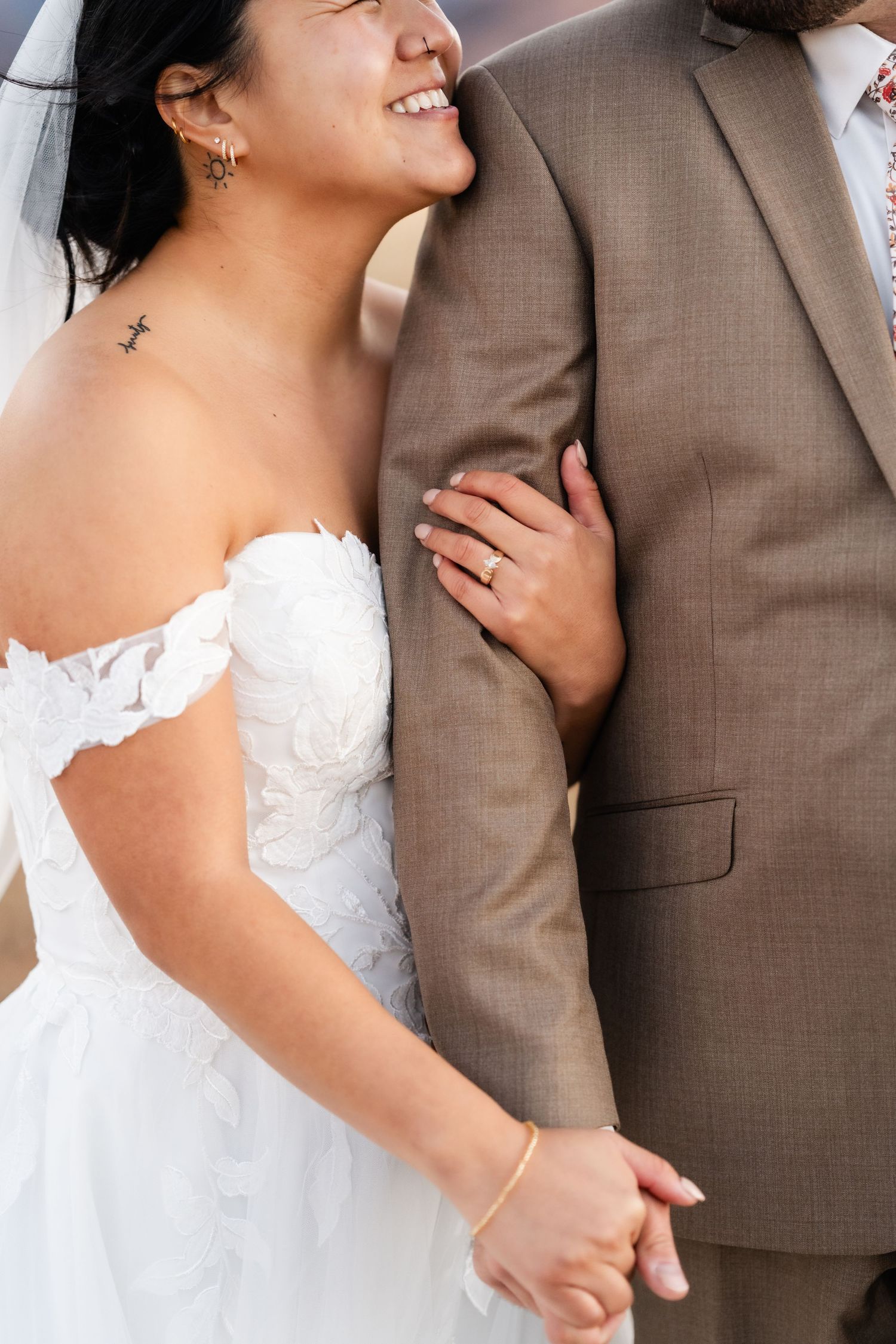 Intimate wedding portrait showing details of white dress against brown suit.