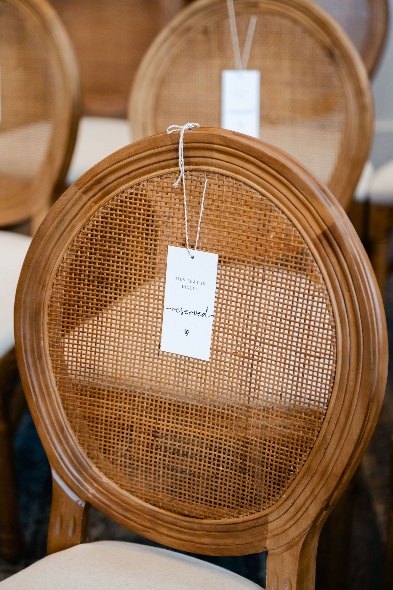 Close-up of a vintage-style dining chair with cane backing and white price tag attached.