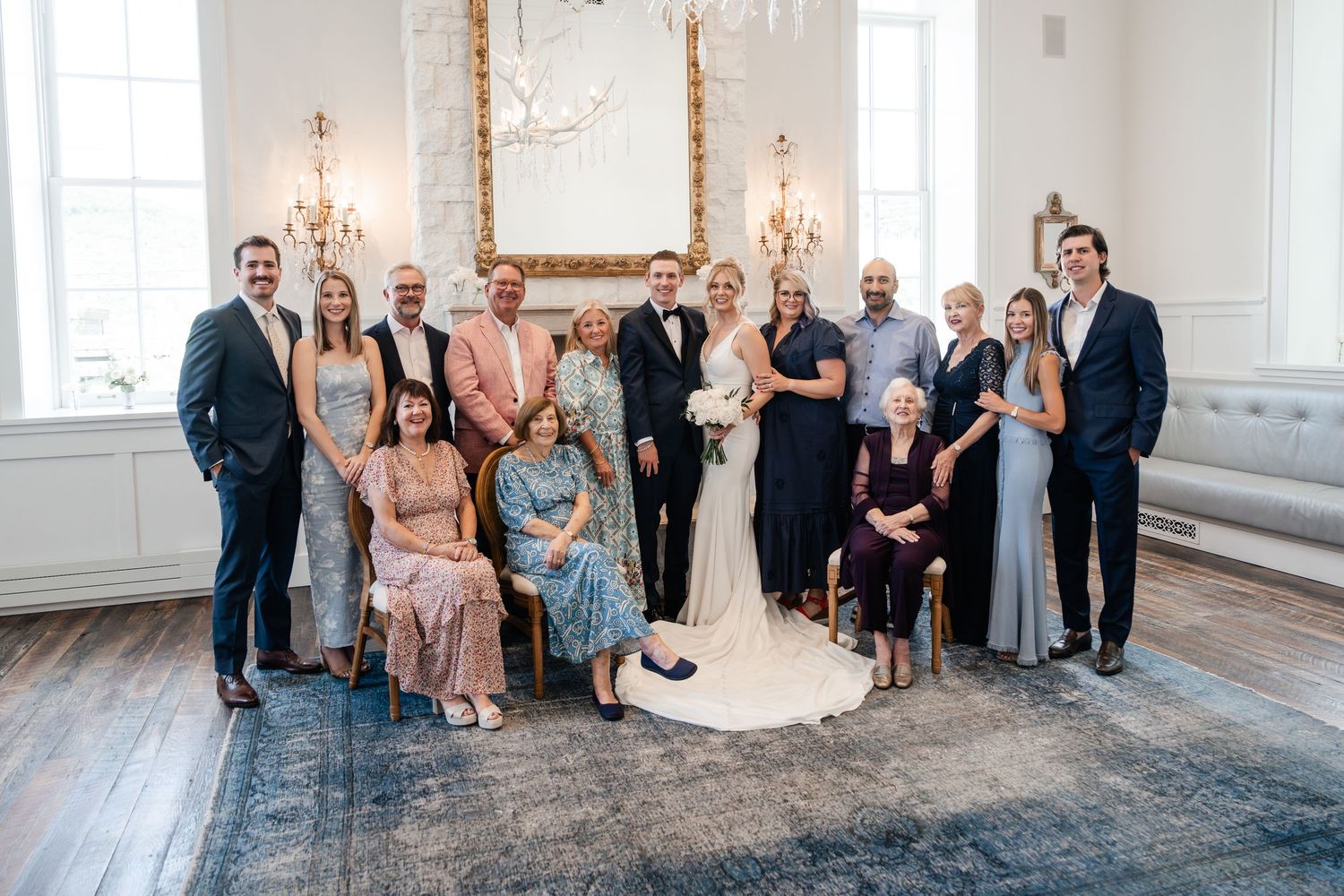 Elegant group portrait in a bright white room with hardwood floors and ornate wall sconces.