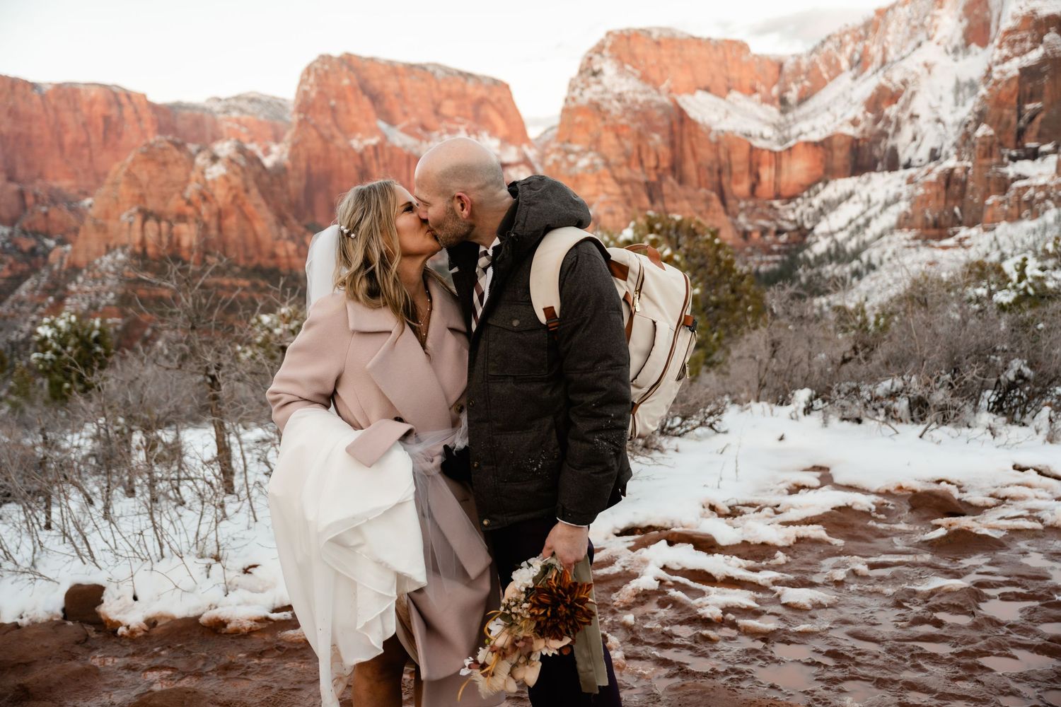 Intimate winter moment on snowy red rock cliffs with canyon backdrop.