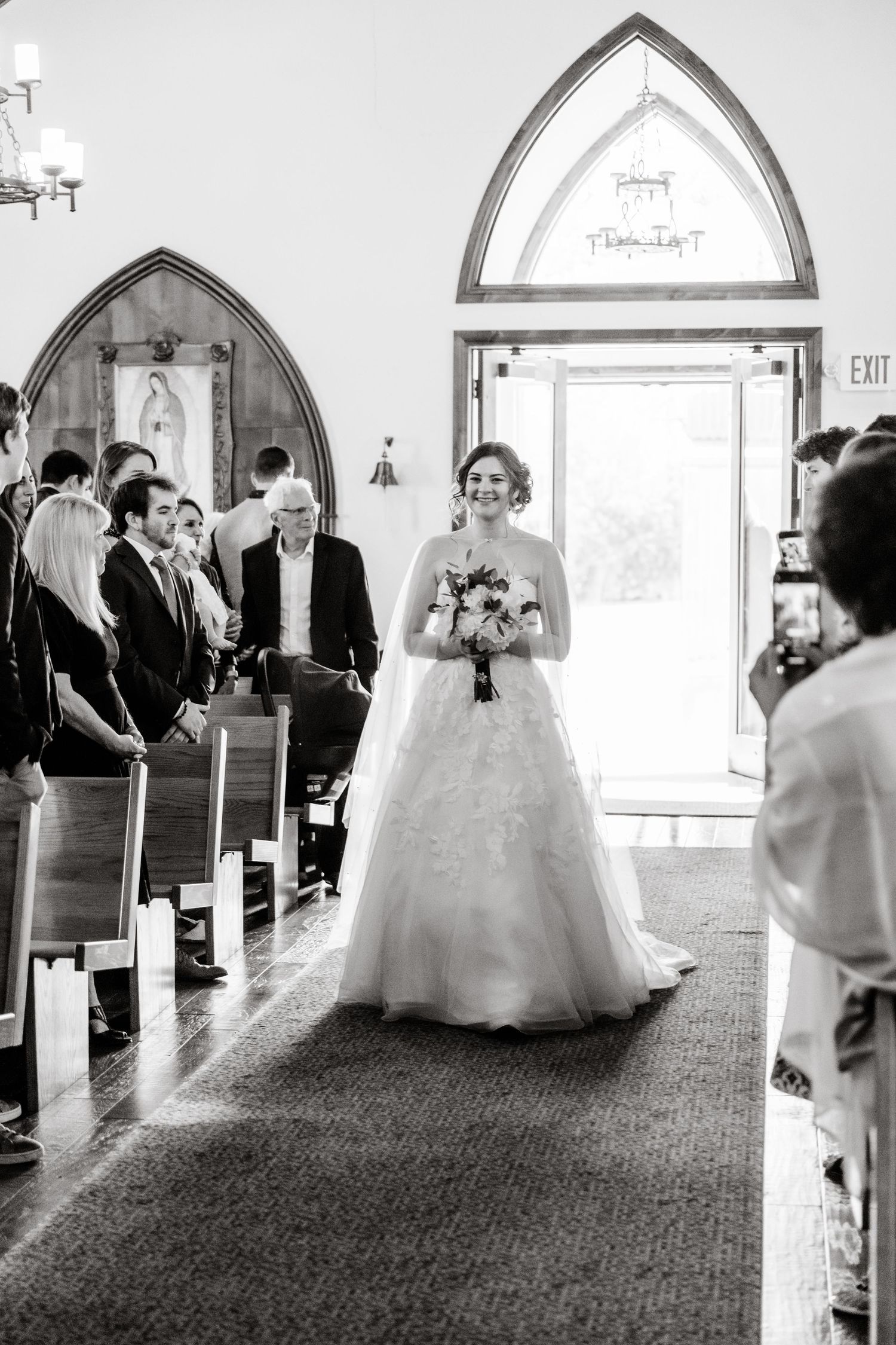 Multiple black and white photos show a wedding ceremony progression inside a church with arched windows and carpeted aisle.
