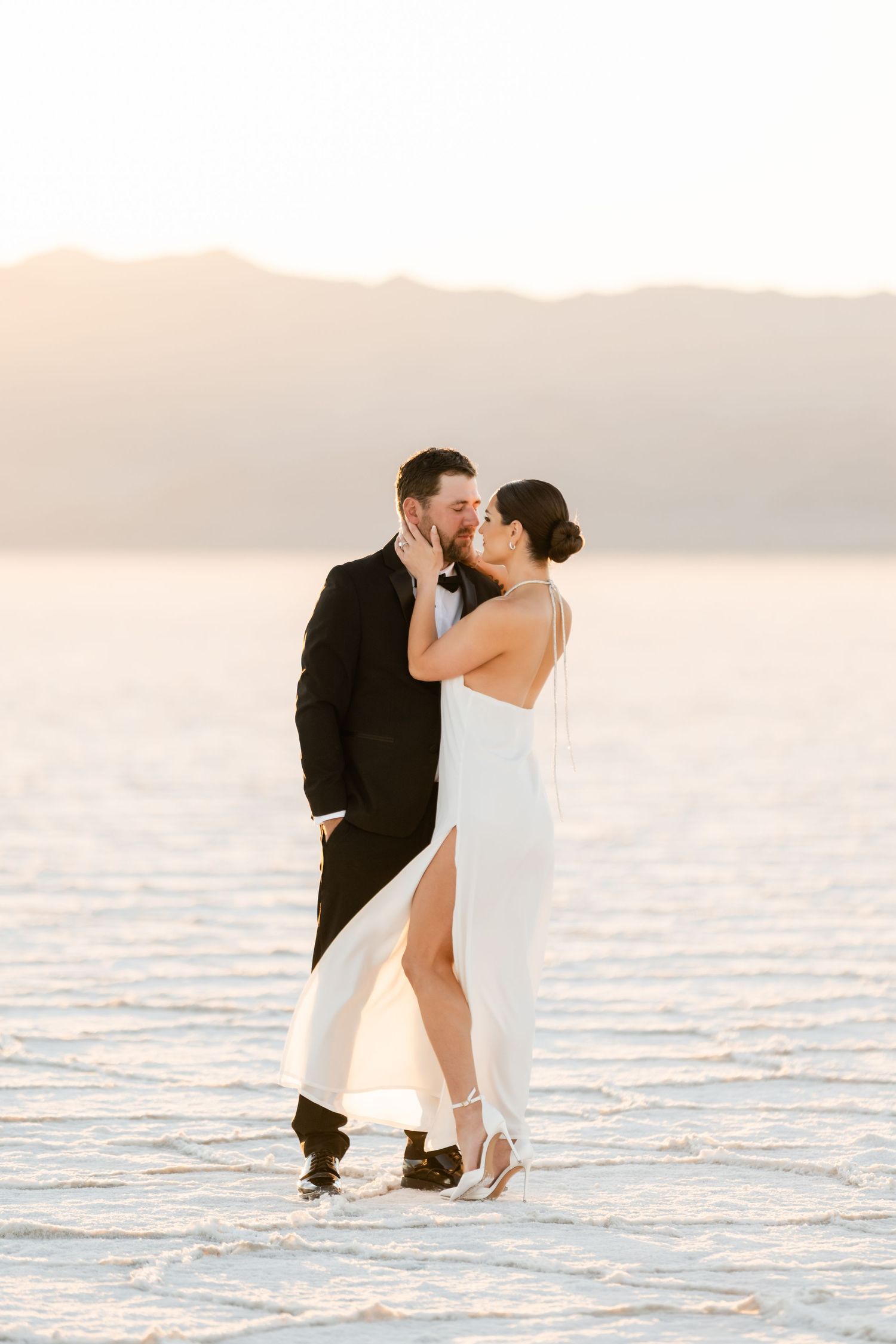 Utah Salt Flats Photographer. A romantic photoshoot on the salt flats at sunset with a couple in formal attire embracing.