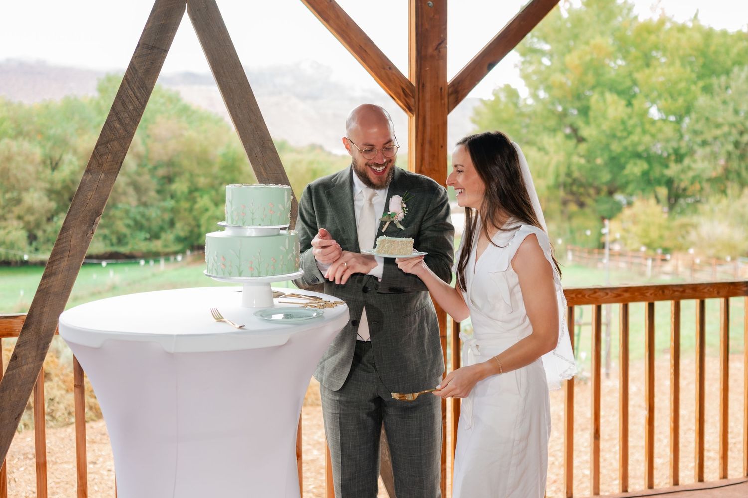A couple shares their first dance at a rustic outdoor wedding venue with wooden beams.