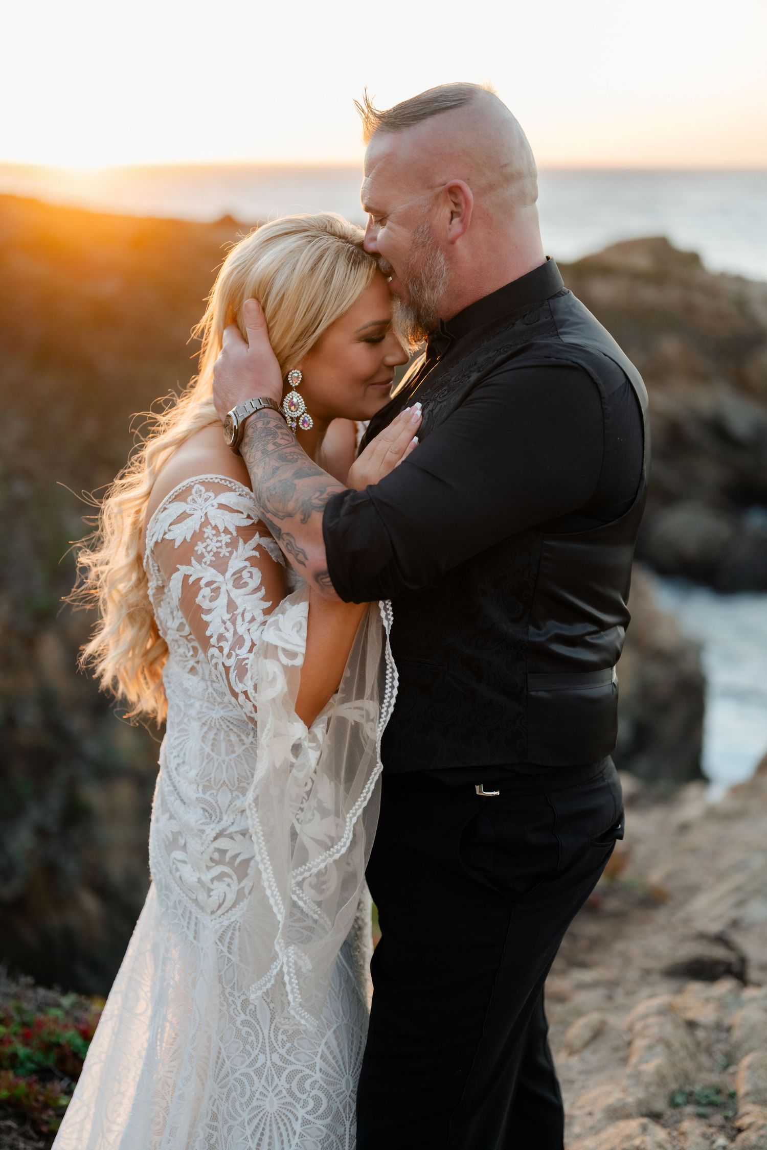 An intimate coastal wedding portrait during sunset with dramatic cliffside scenery.