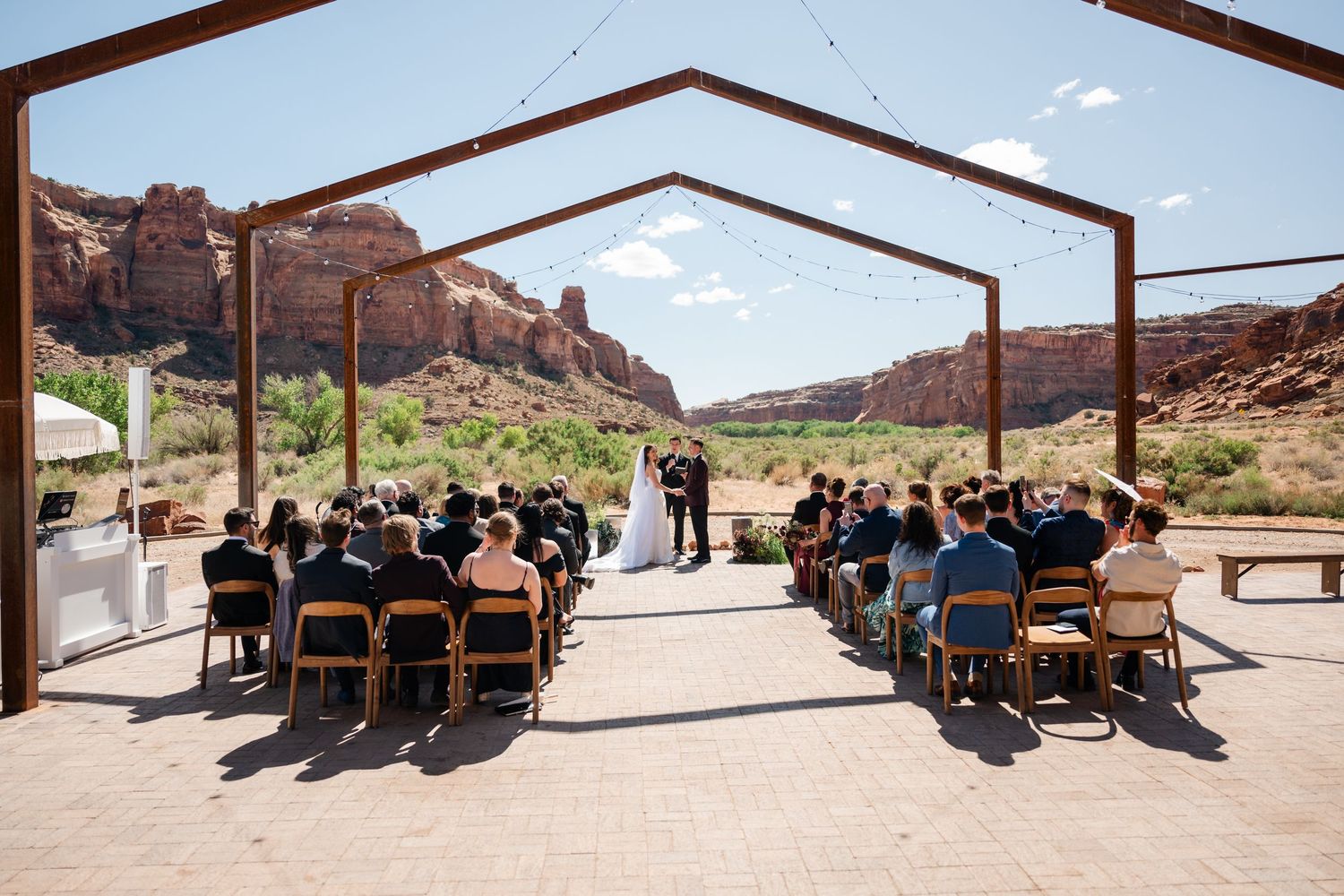 Outdoor wedding ceremony under a rustic pergola with red rock canyon views in Moab, Utah.