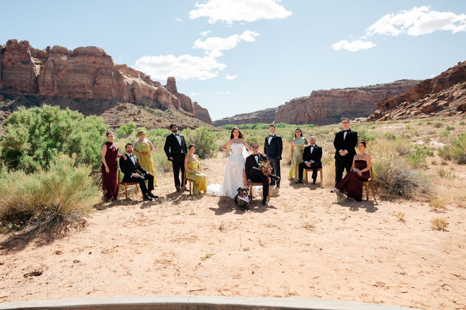 Wedding party poses in rustic desert canyon landscape with red rock formations outside of the Red Earth Venue in Moab, Utah.