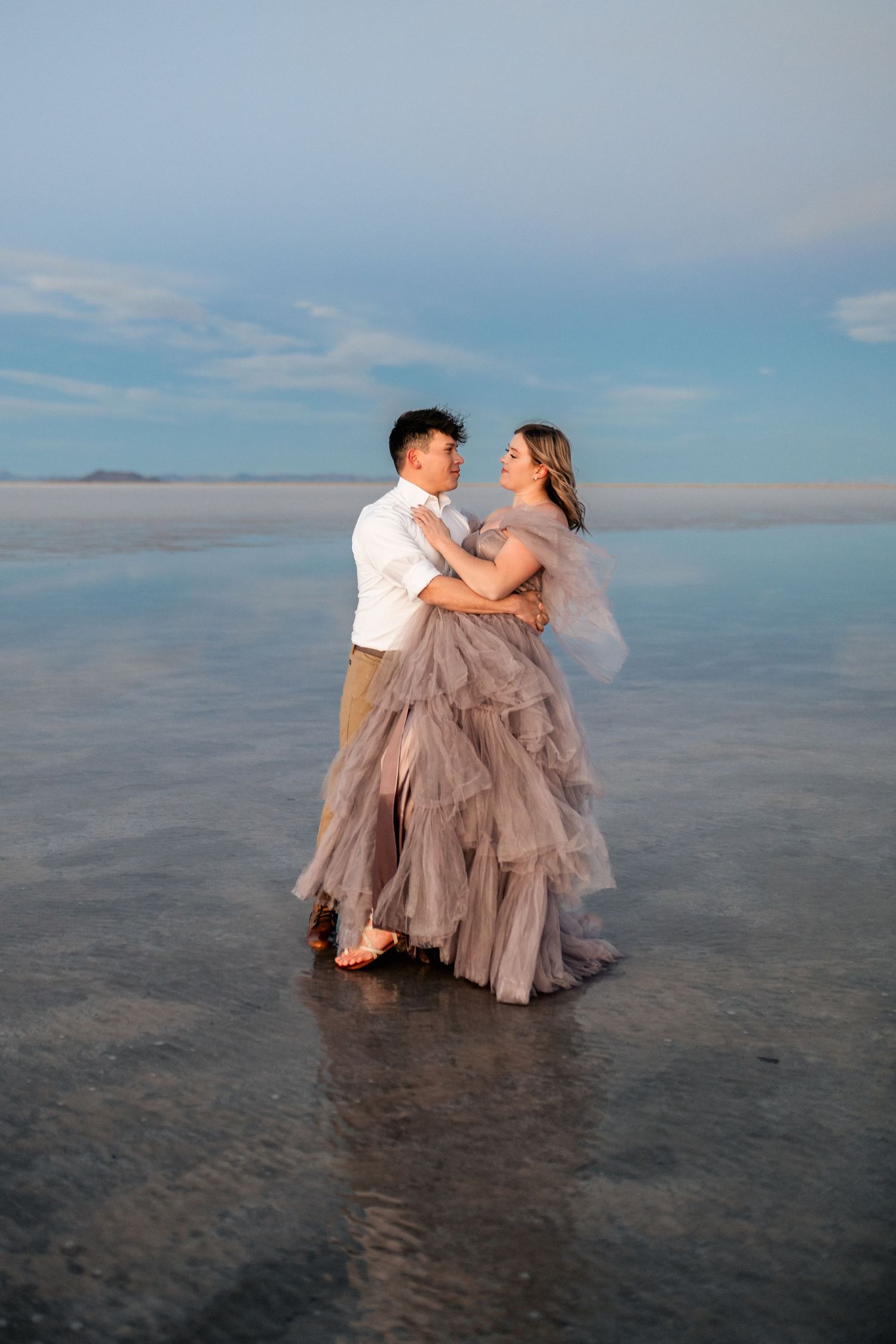 Romantic moment captured as the couple embraces amidst the serene beauty of the flooded Salt Flats during blue hour