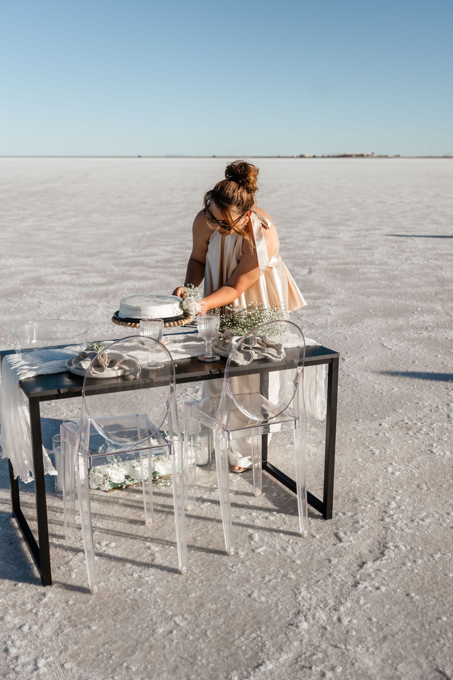 Modern clear acrylic furniture setup on a stark white salt flat landscape under blue sky.