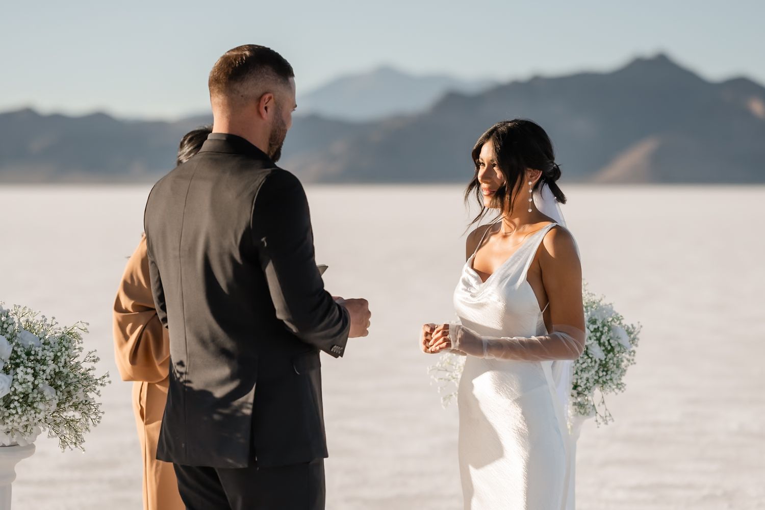 Intimate wedding ceremony moments captured on salt flats with mountain backdrop.