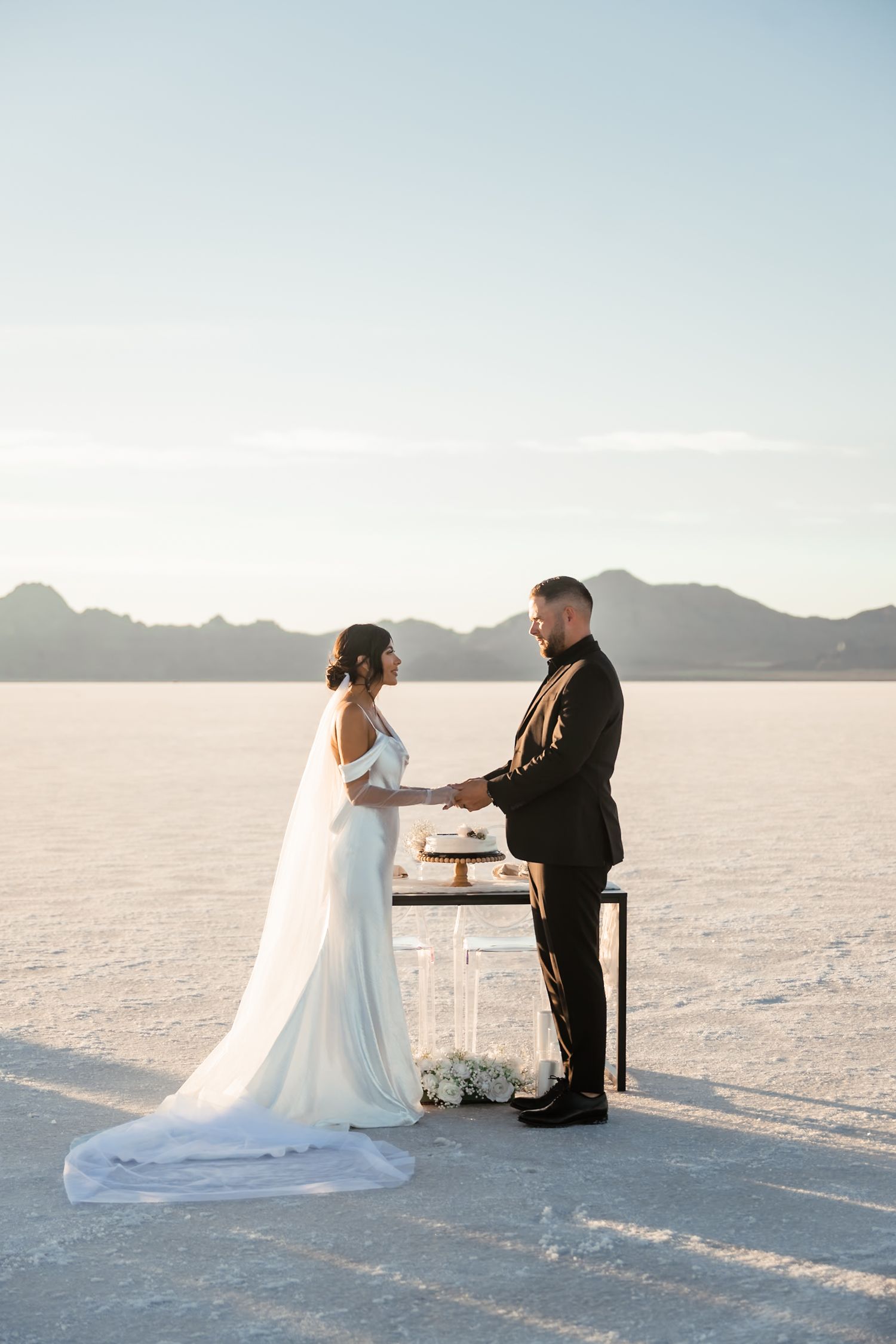 Wedding ceremony setup on vast salt flats with mountains in distance.
