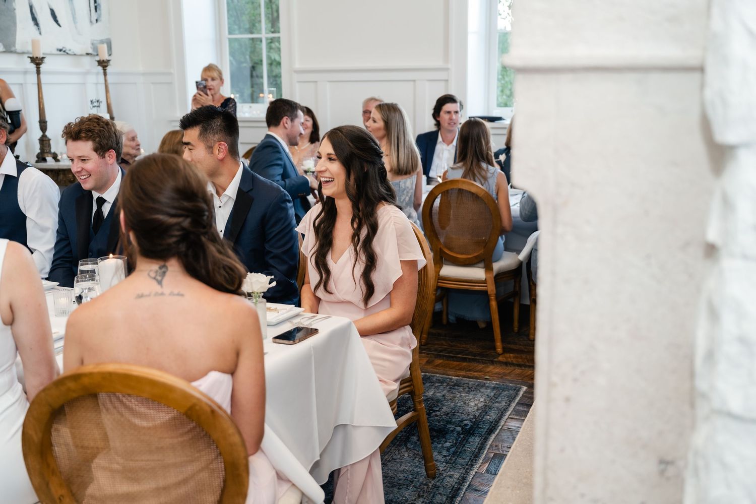 Guests seated at round tables during an elegant indoor wedding reception.