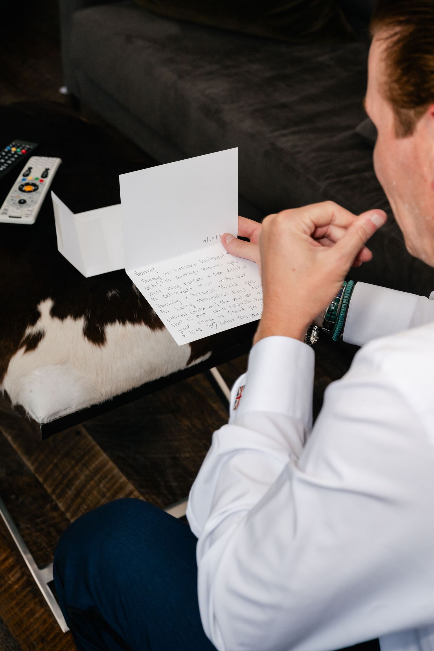 Person in white shirt writes handwritten note on dark wooden surface.
