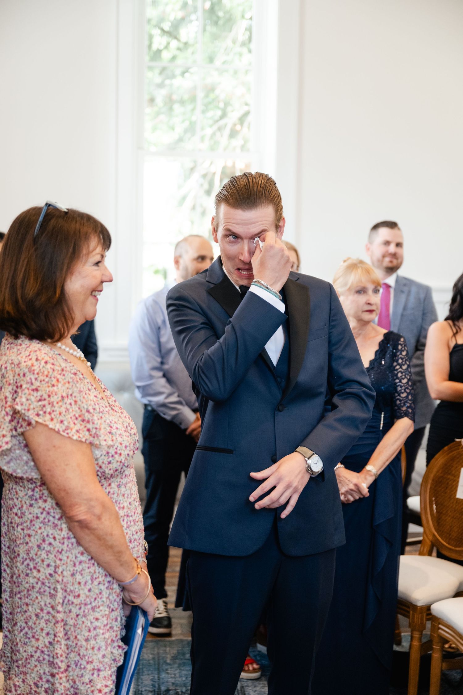 Wedding guests share emotional reactions and embraces during a special moment at the ceremony.