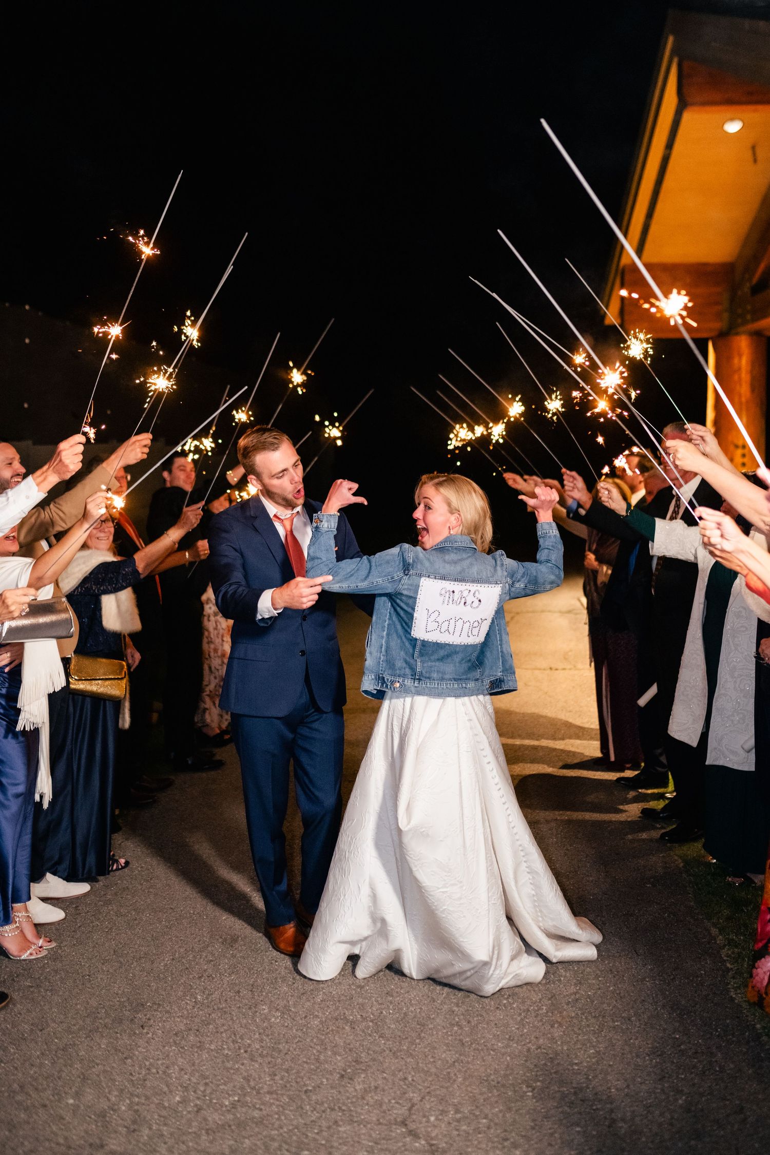 Wedding guests form a sparkler exit tunnel during nighttime celebration.