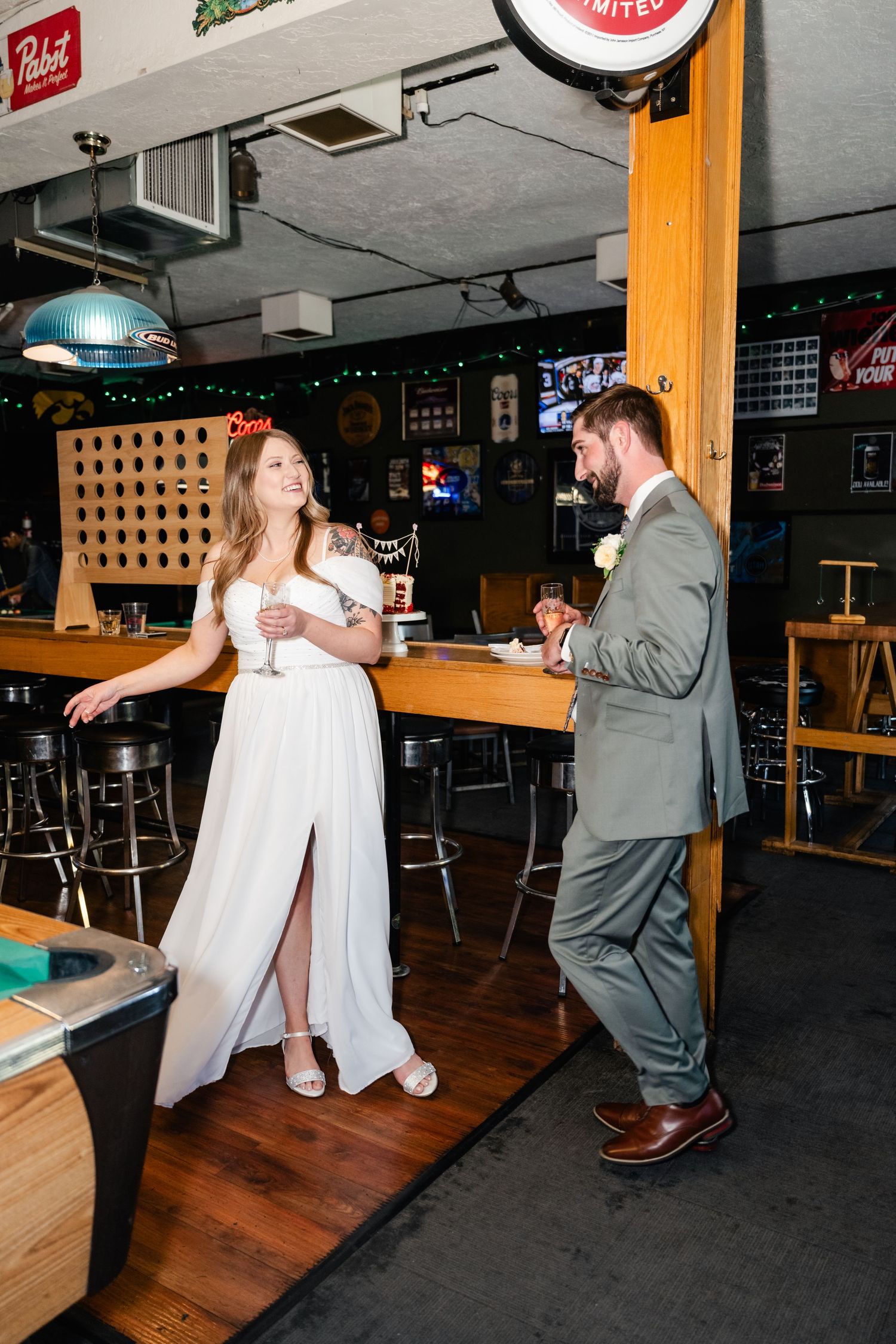 A couple dances together in a dimly lit bar or restaurant with wooden decor and neon signs on the walls.