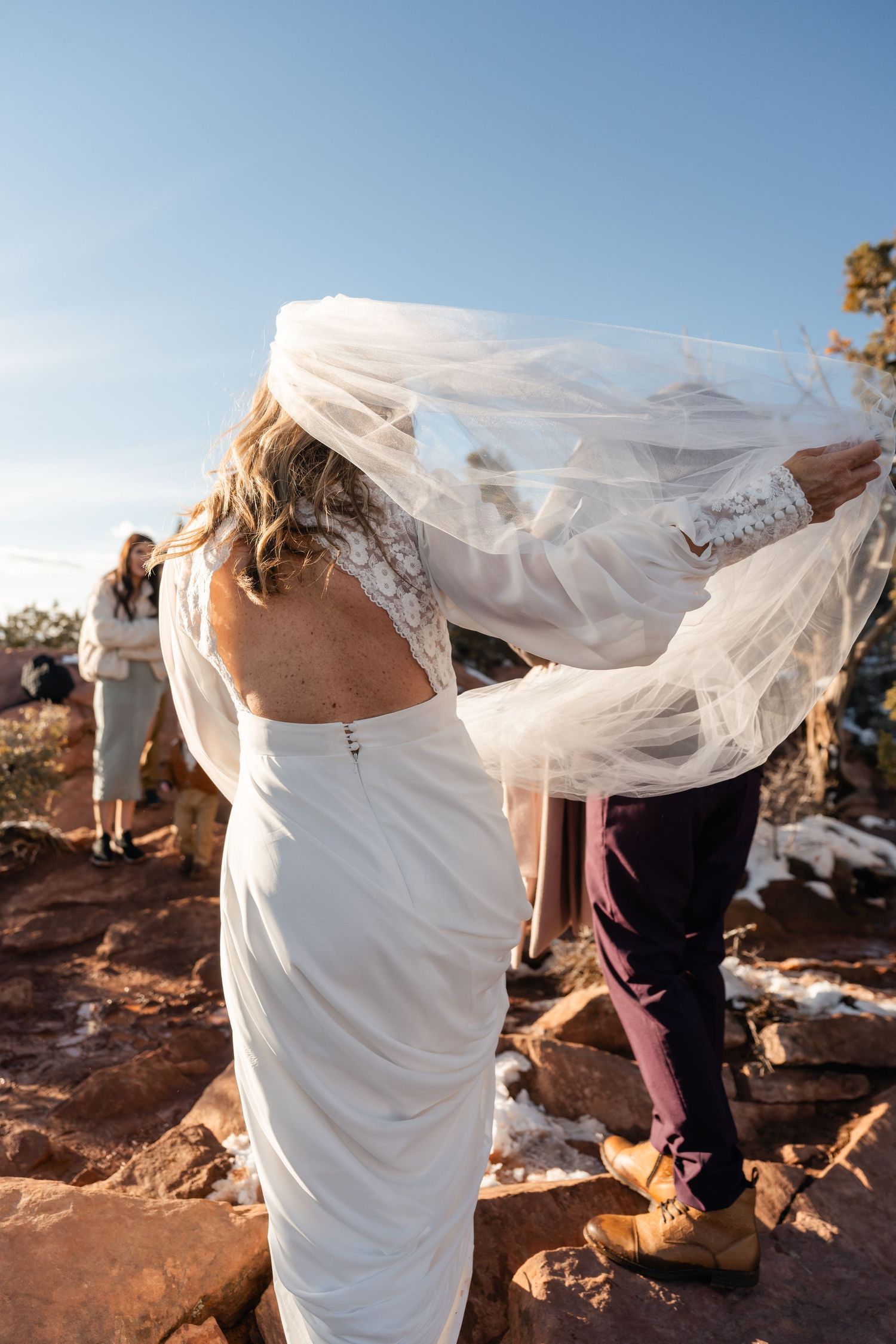 Flowing white veil catches wind against red rock desert landscape.