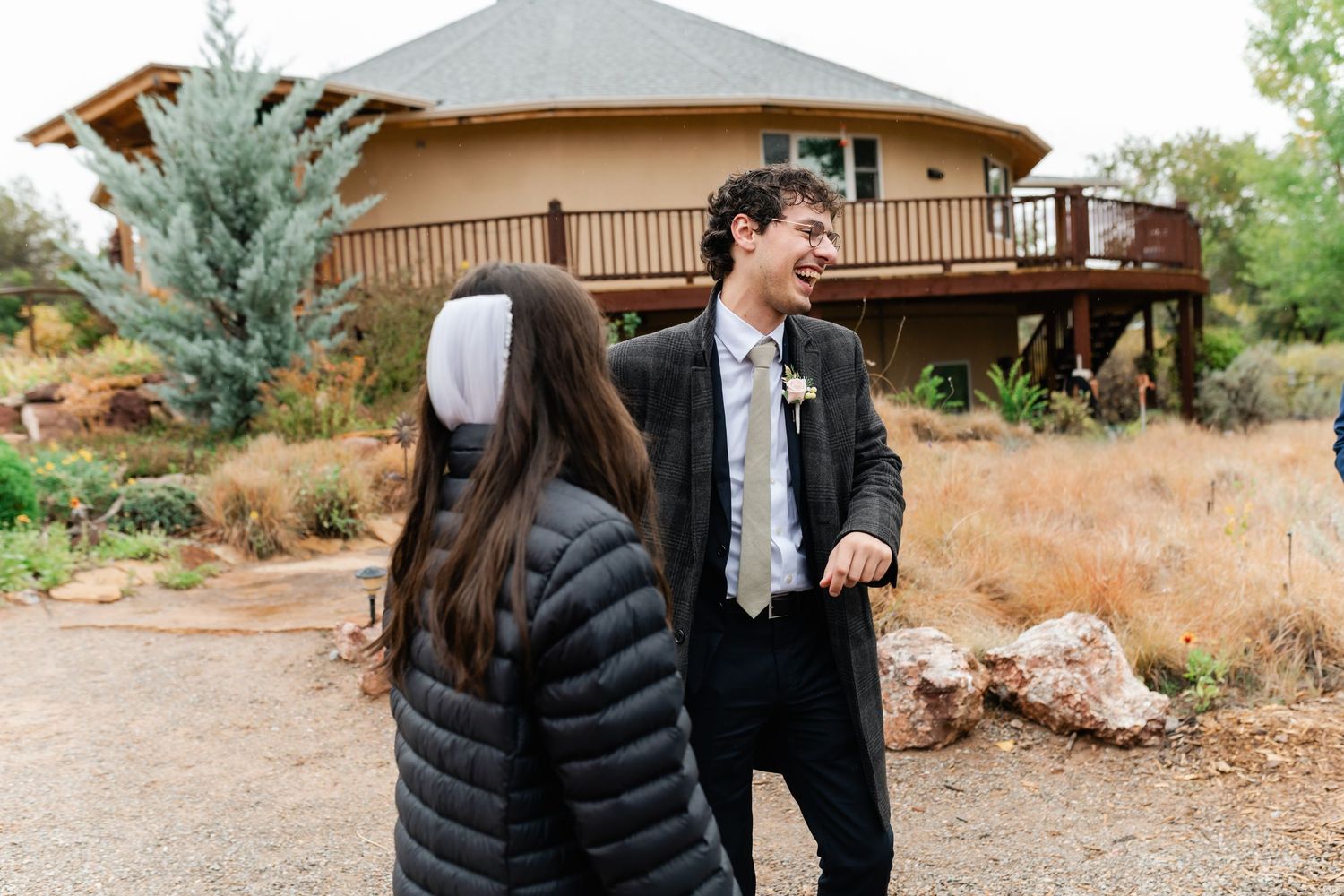 Guests interacting outside rustic venue with desert landscape in background.