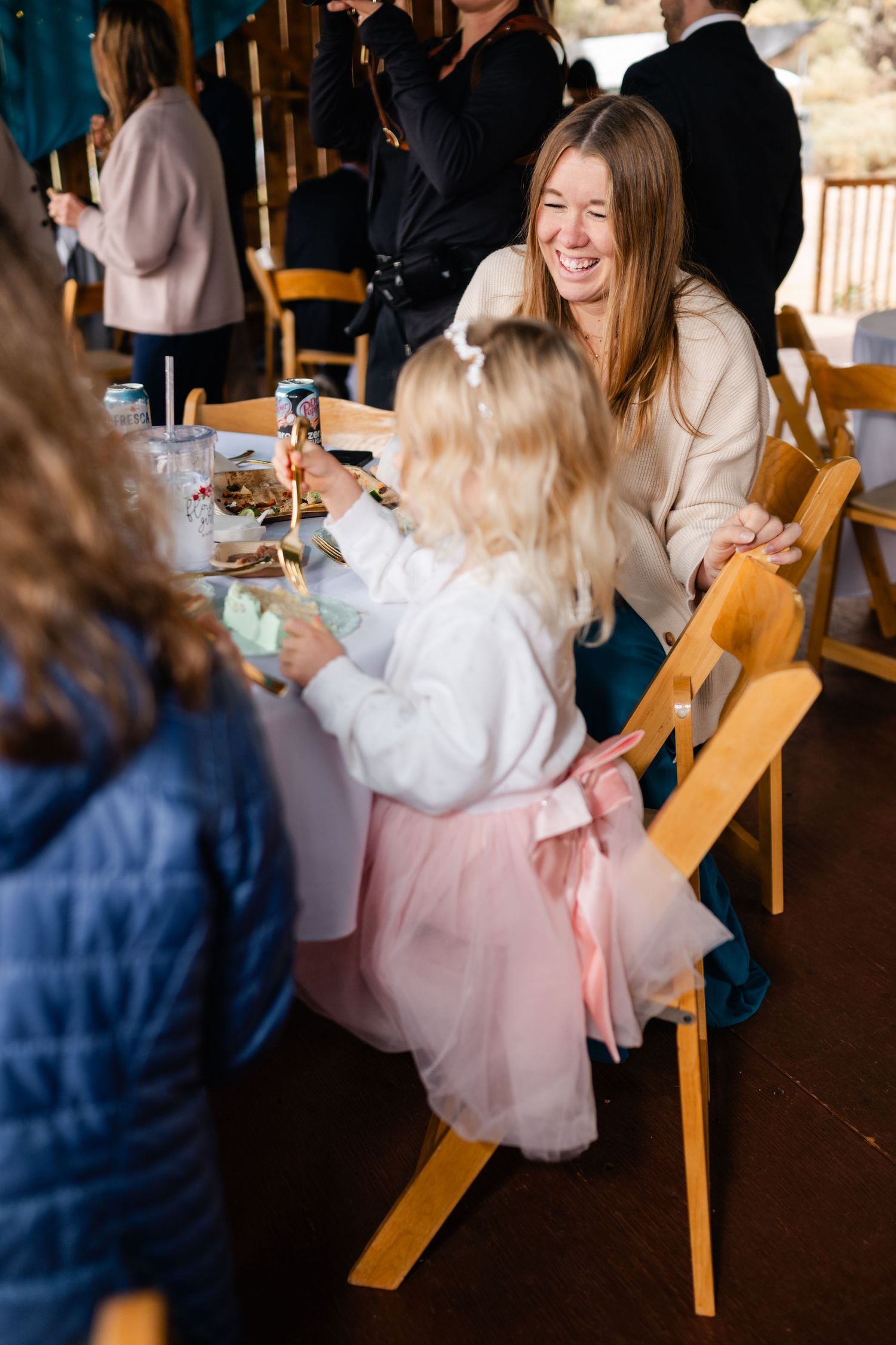Wedding reception guests enjoying a casual dining moment at wooden tables.