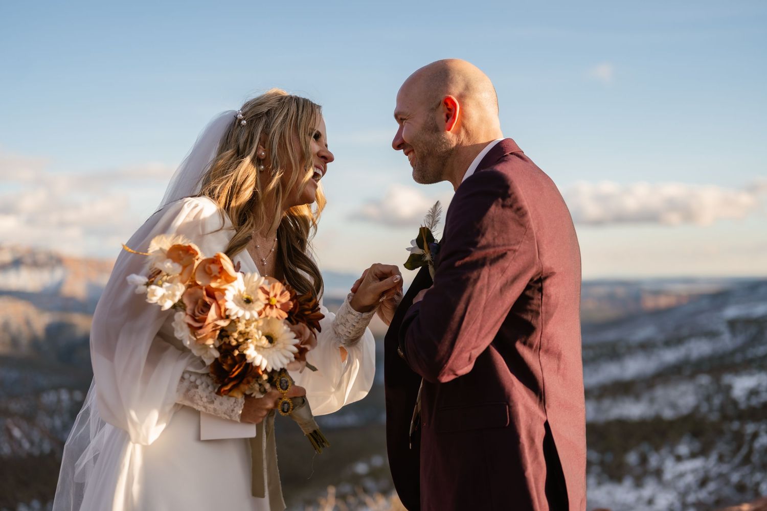Couple sharing intimate moment on snowy mountain overlook at sunset.