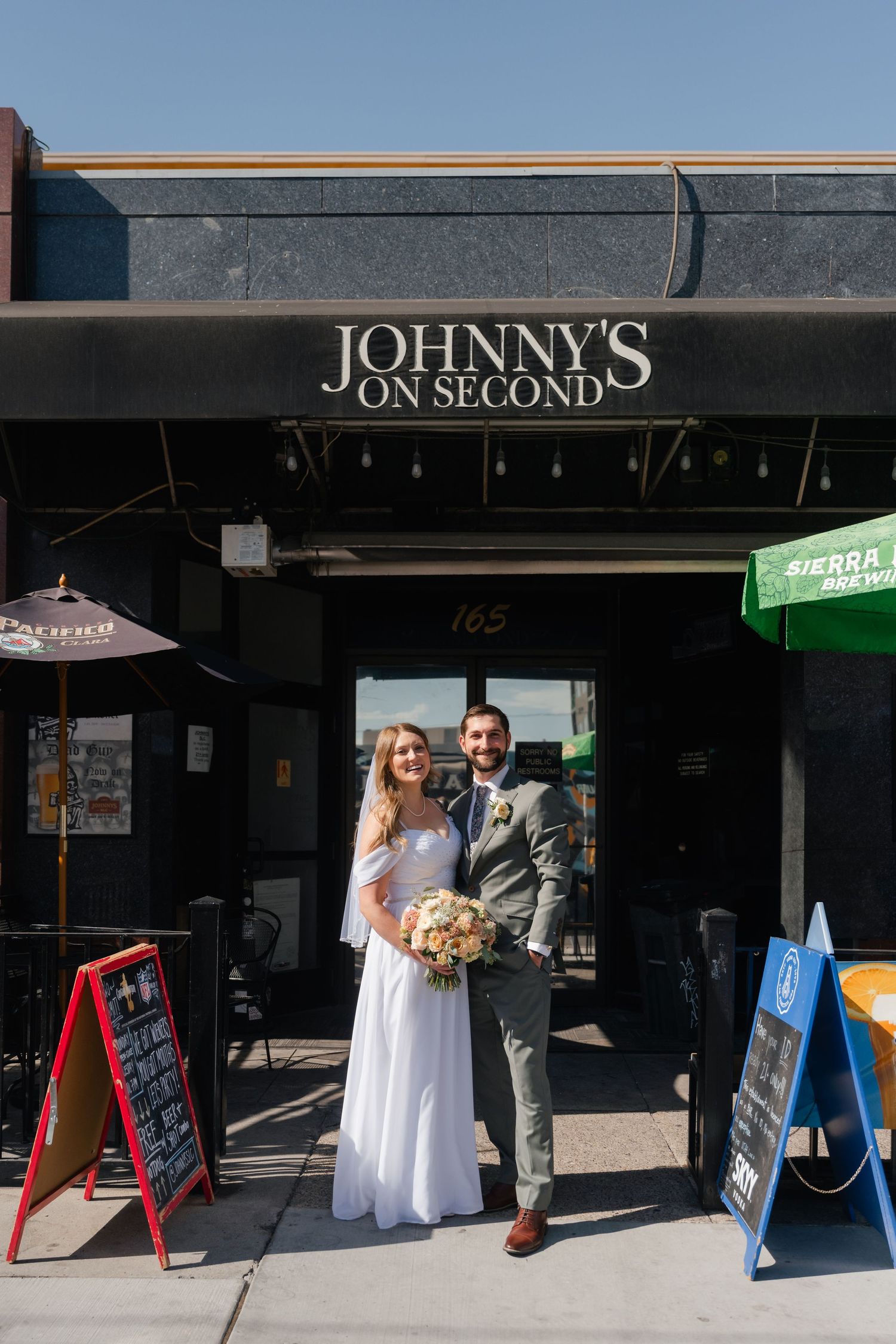 A couple poses in wedding attire outside Johnny's on Second establishment.