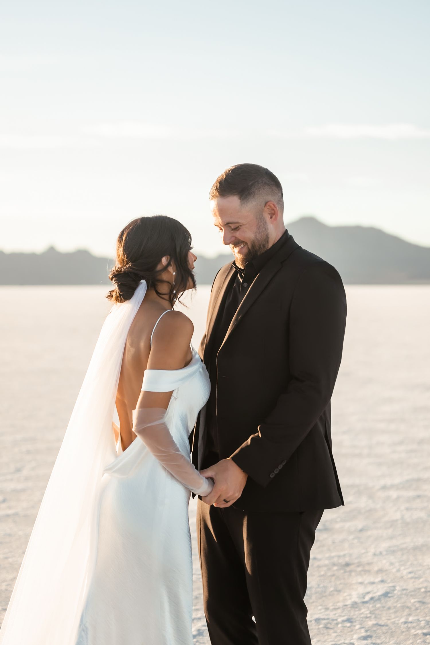 Intimate wedding moment captured on salt flats with mountains in background.