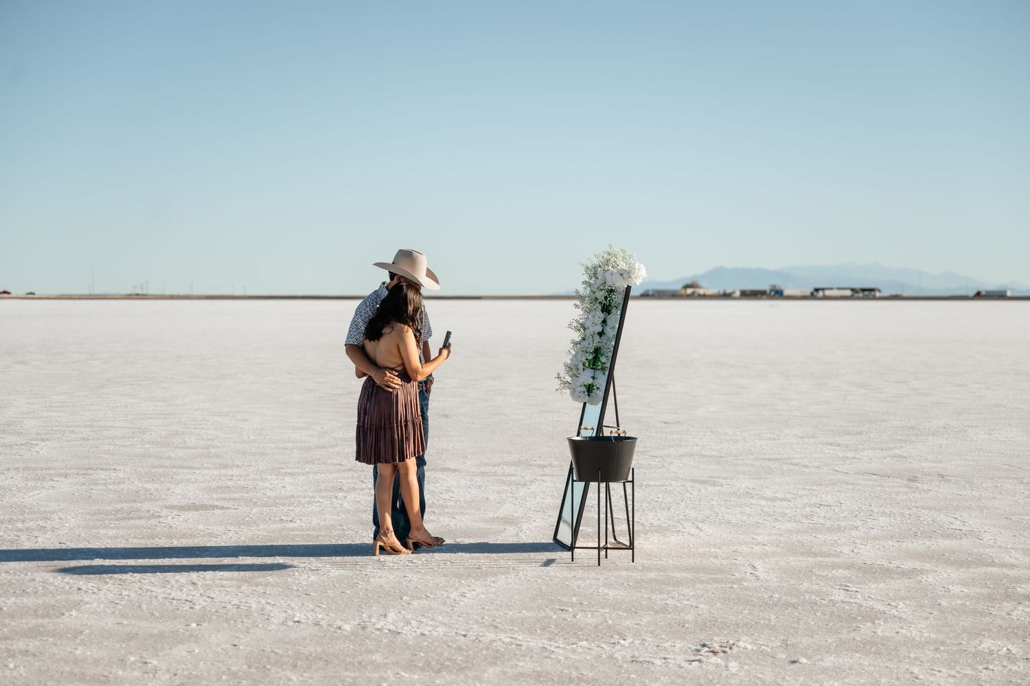 Wedding ceremony setup with chairs on vast salt flats under clear blue skies.