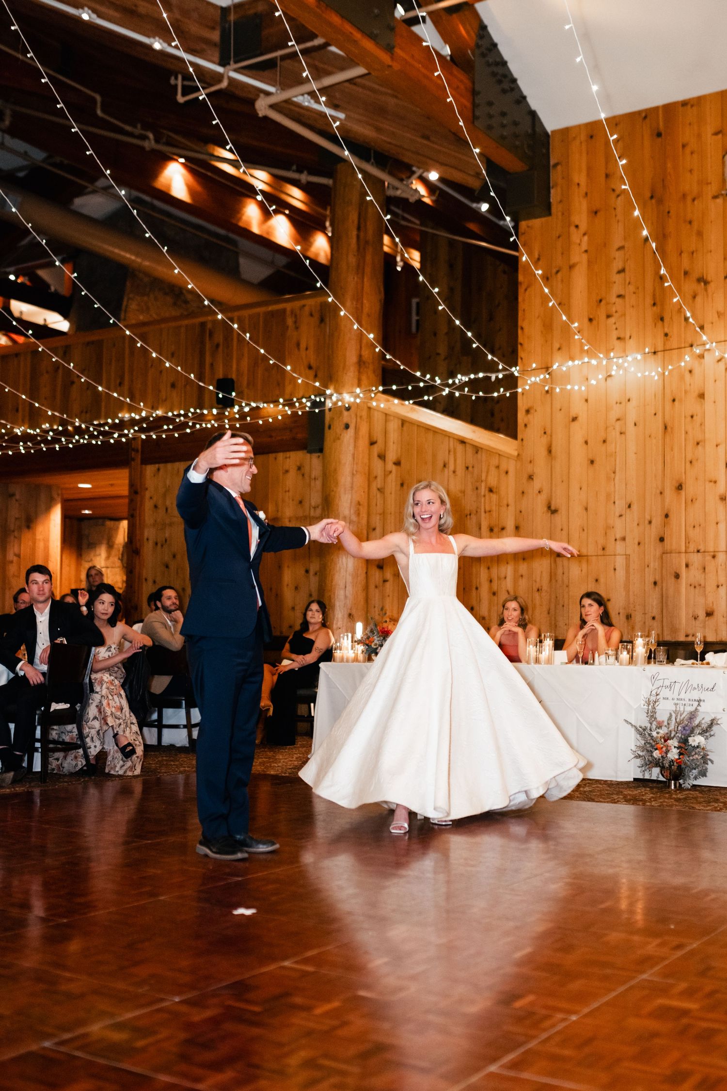 Wedding celebration in a log cabin venue with twinkle lights and wooden dance floor.