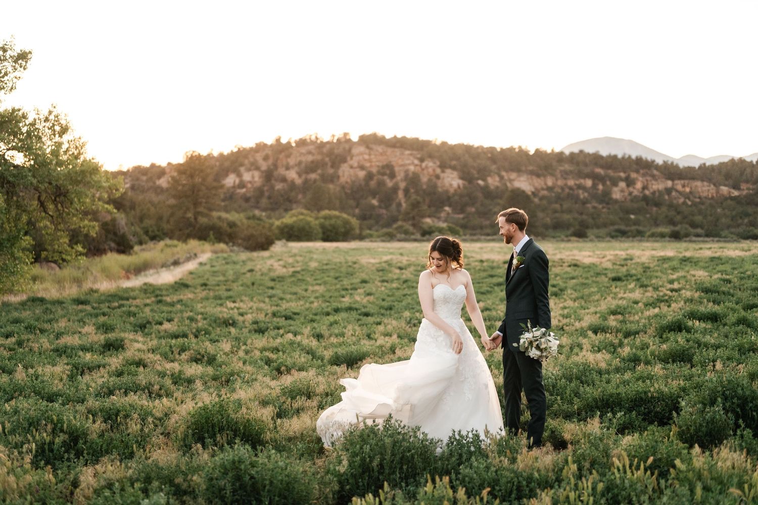 Romantic wedding portraits captured in a scenic mountain meadow during golden hour.