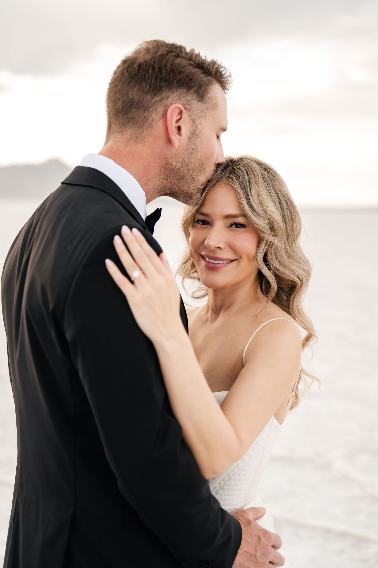 Salt Flats Elopement Photographer. A tender moment between a bride and groom against a cloudy sky on salt flats.