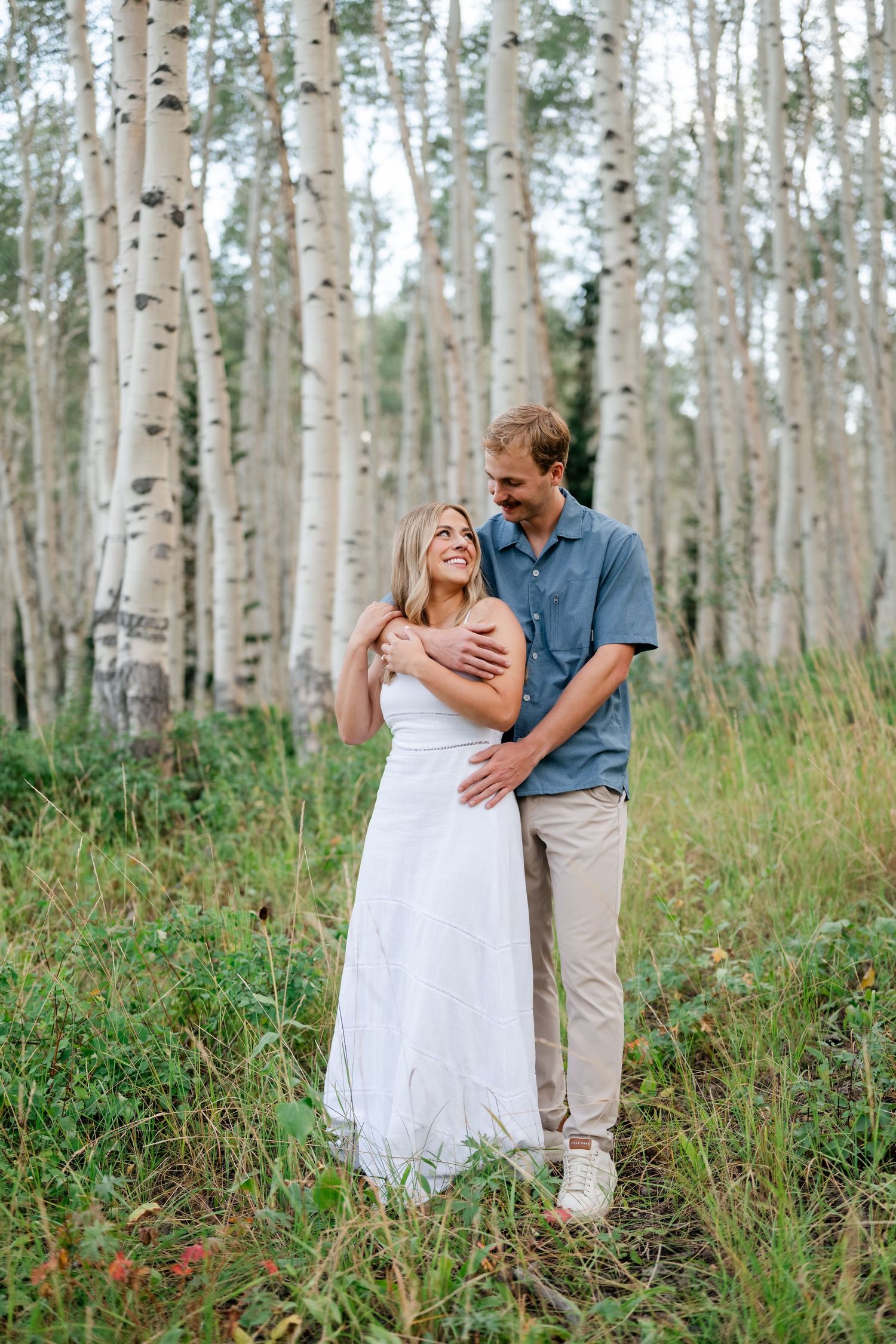 Couple embracing in an aspen forest, surrounded by lush greenery at their engagements near Park City and Deer Valley.