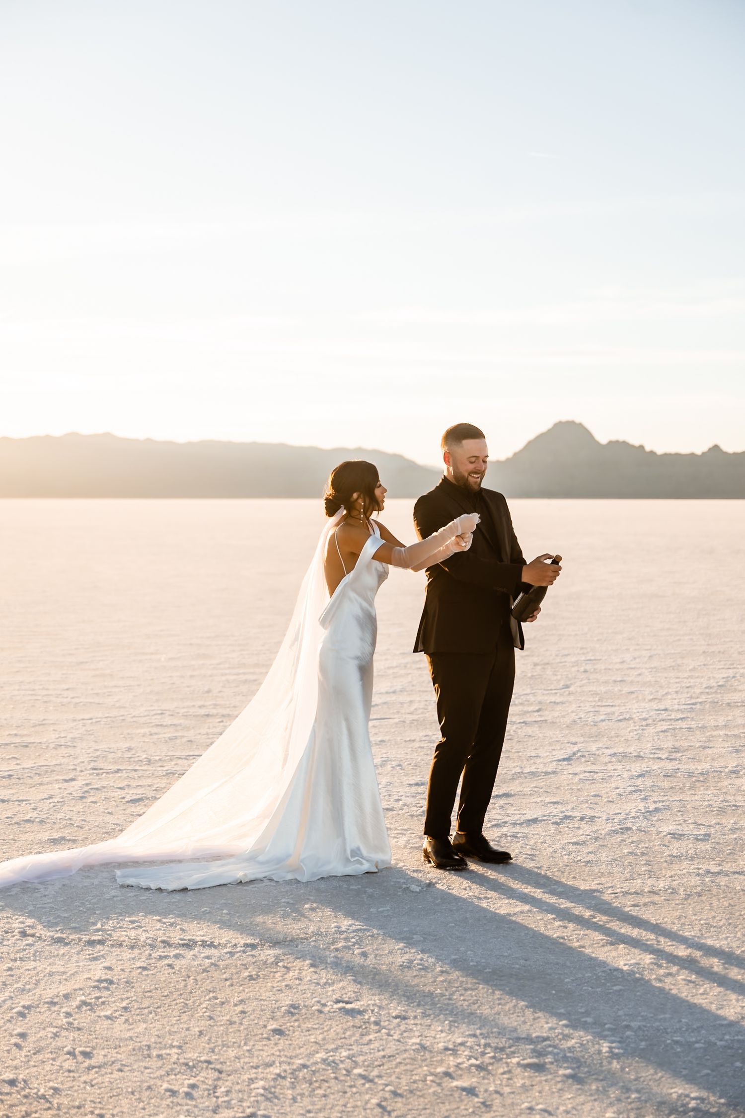 A couple dances playfully on the vast white salt flats during their wedding photoshoot.