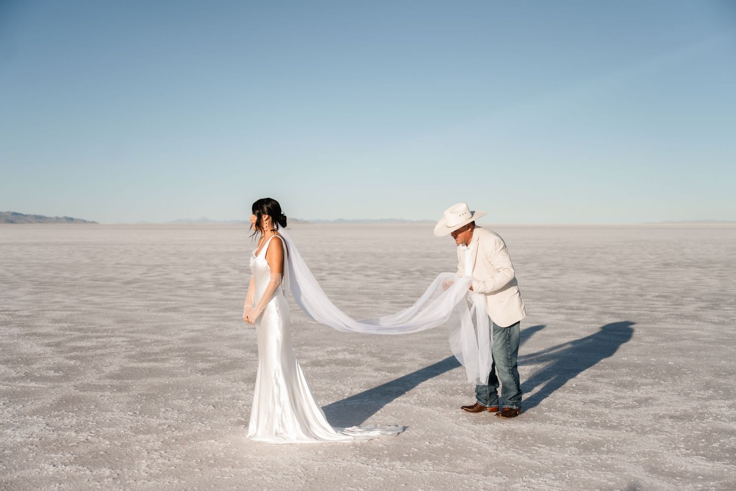 Wedding couple walking on the salt flats with flowing white dress and veil.