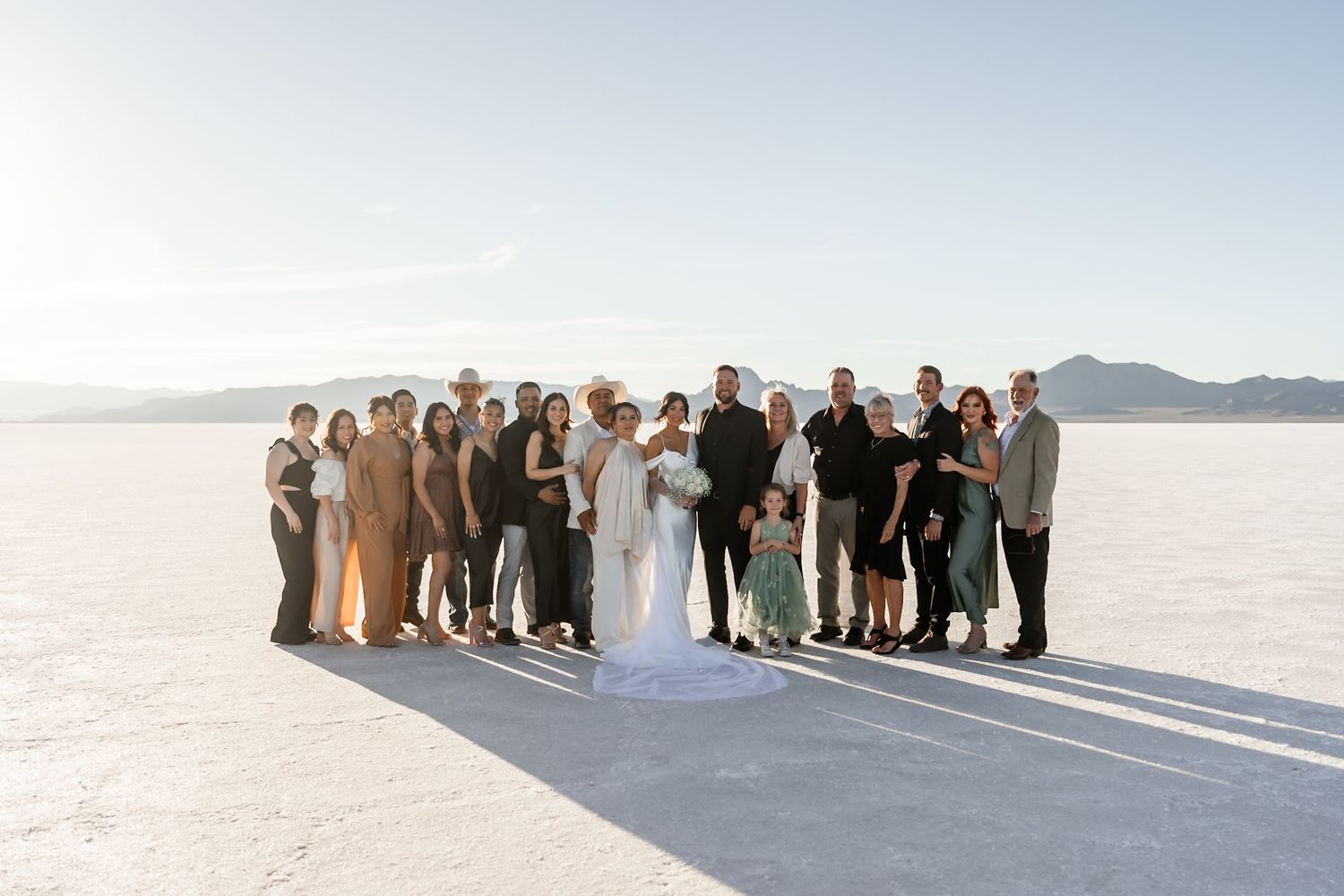Wide shot of wedding party and guests gathered on salt flats for ceremony.