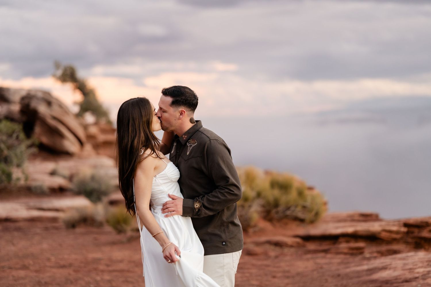 A romantic moment captured at sunset on red rock formations in the desert landscape.