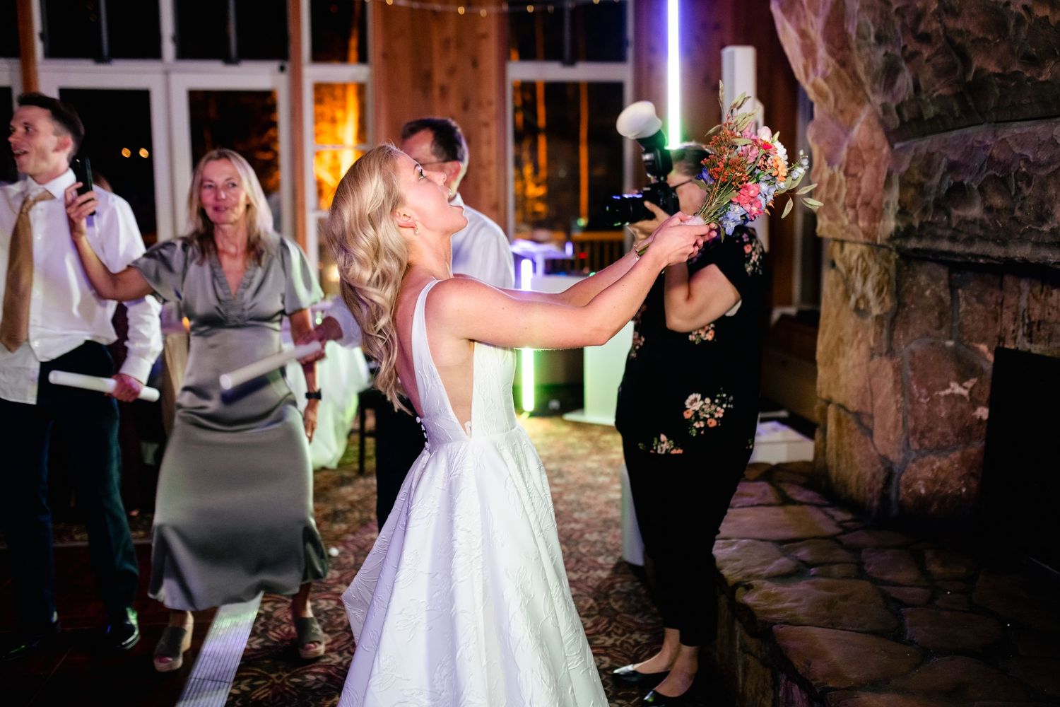 Evening wedding reception with couples dancing under warm lighting in rustic venue.